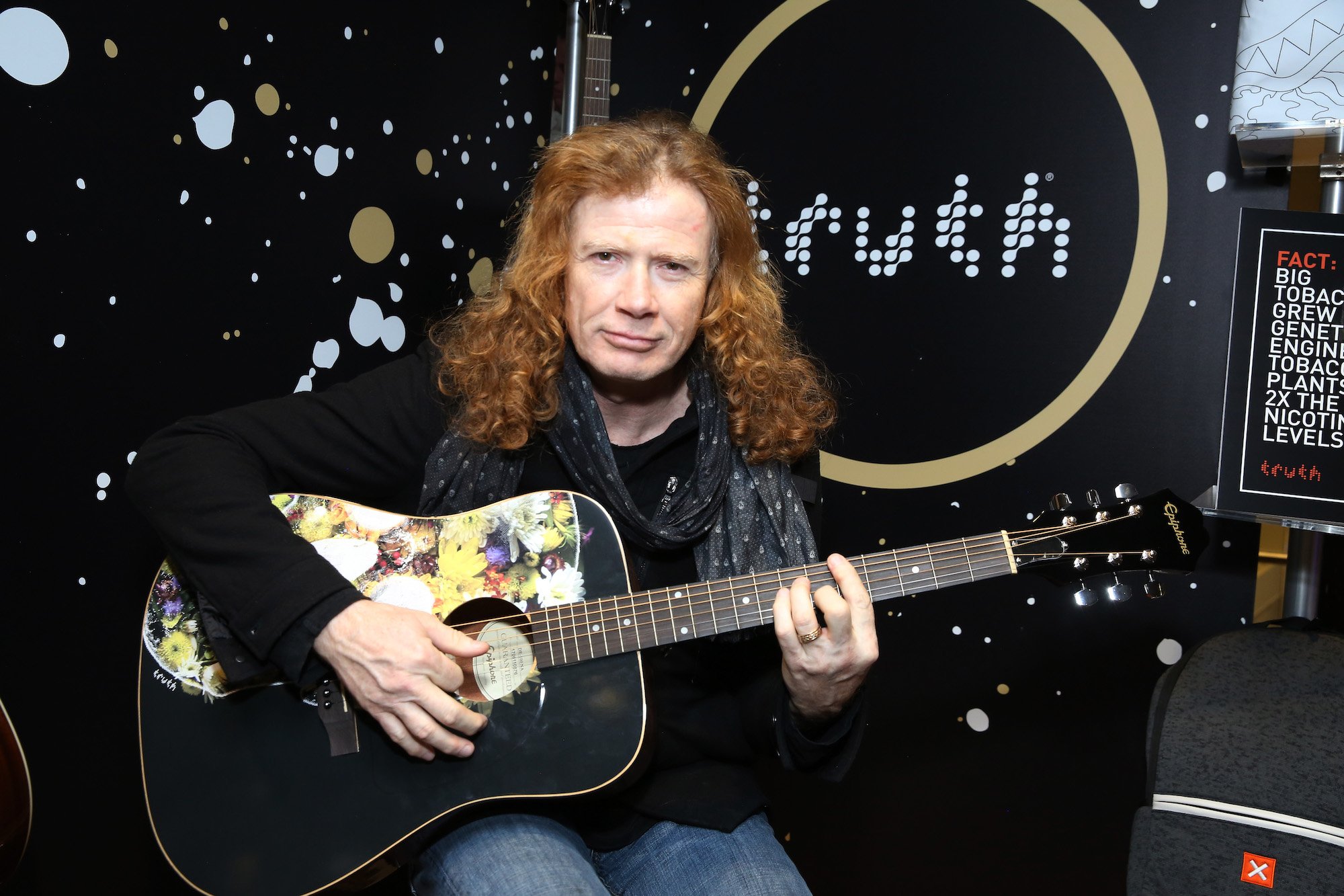 Dave Mustaine slightly smiling, holding a guitar