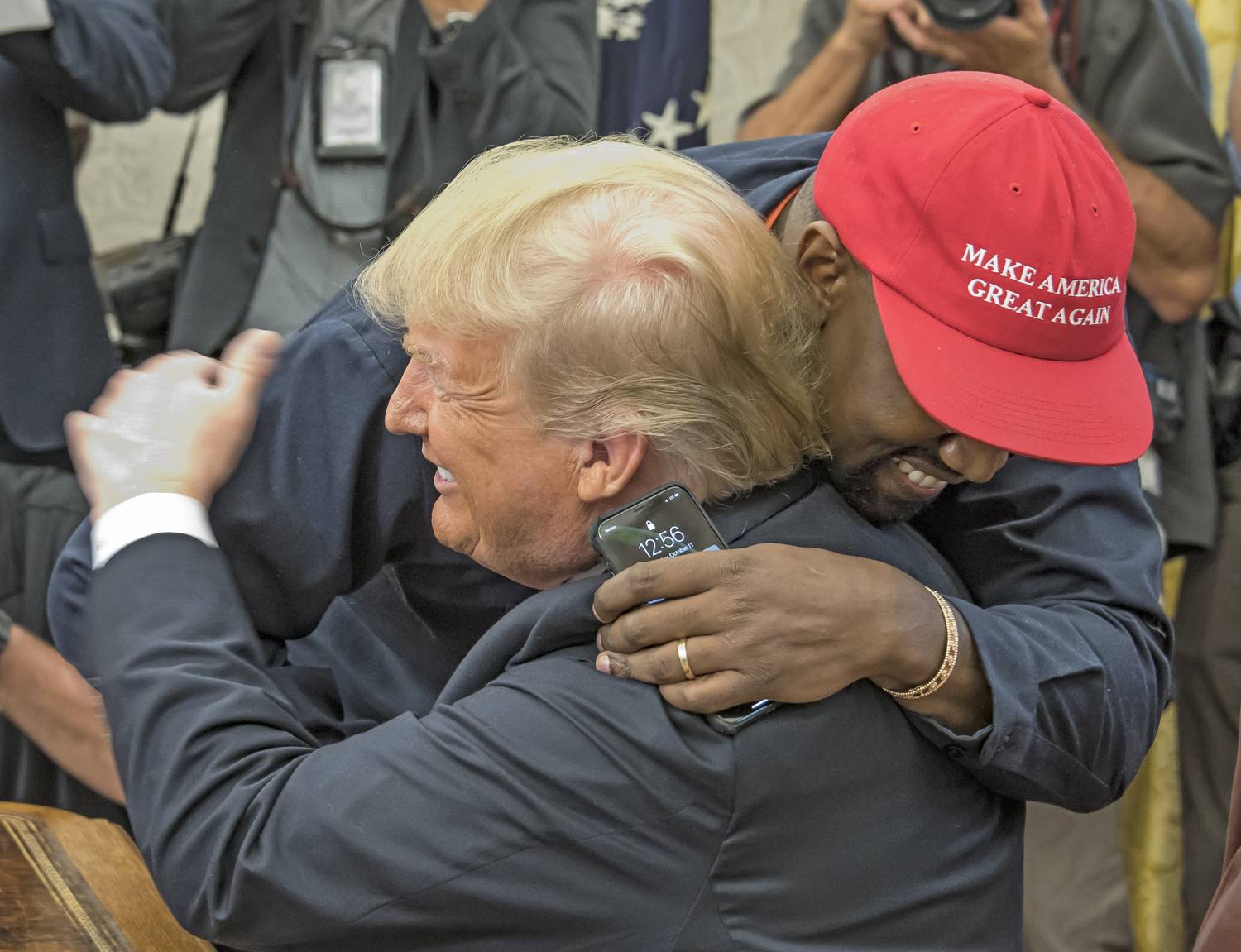 American rapper and producer Kanye West embraces real estate developer and US President Donald Trump in the White House's Oval Office, Washington DC, October 11, 2018. West wears a red baseball cap that reads 'Make America Great Again,' Trump's campaign slogan.