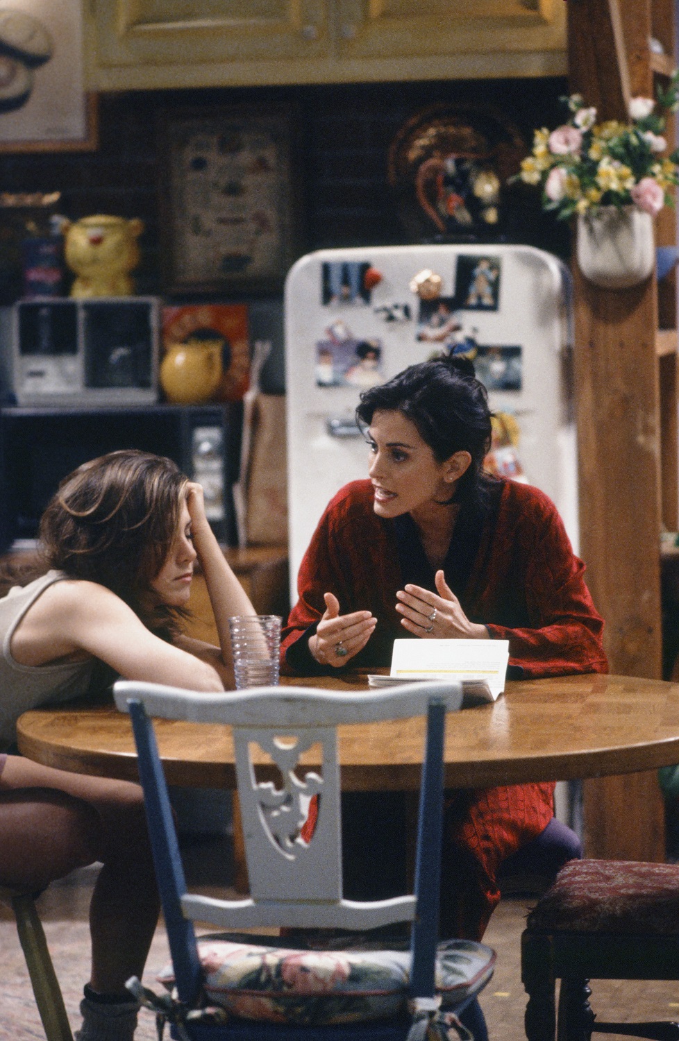 Rachel Green and Monica Geller sit at their kitchen table in 'Friends'