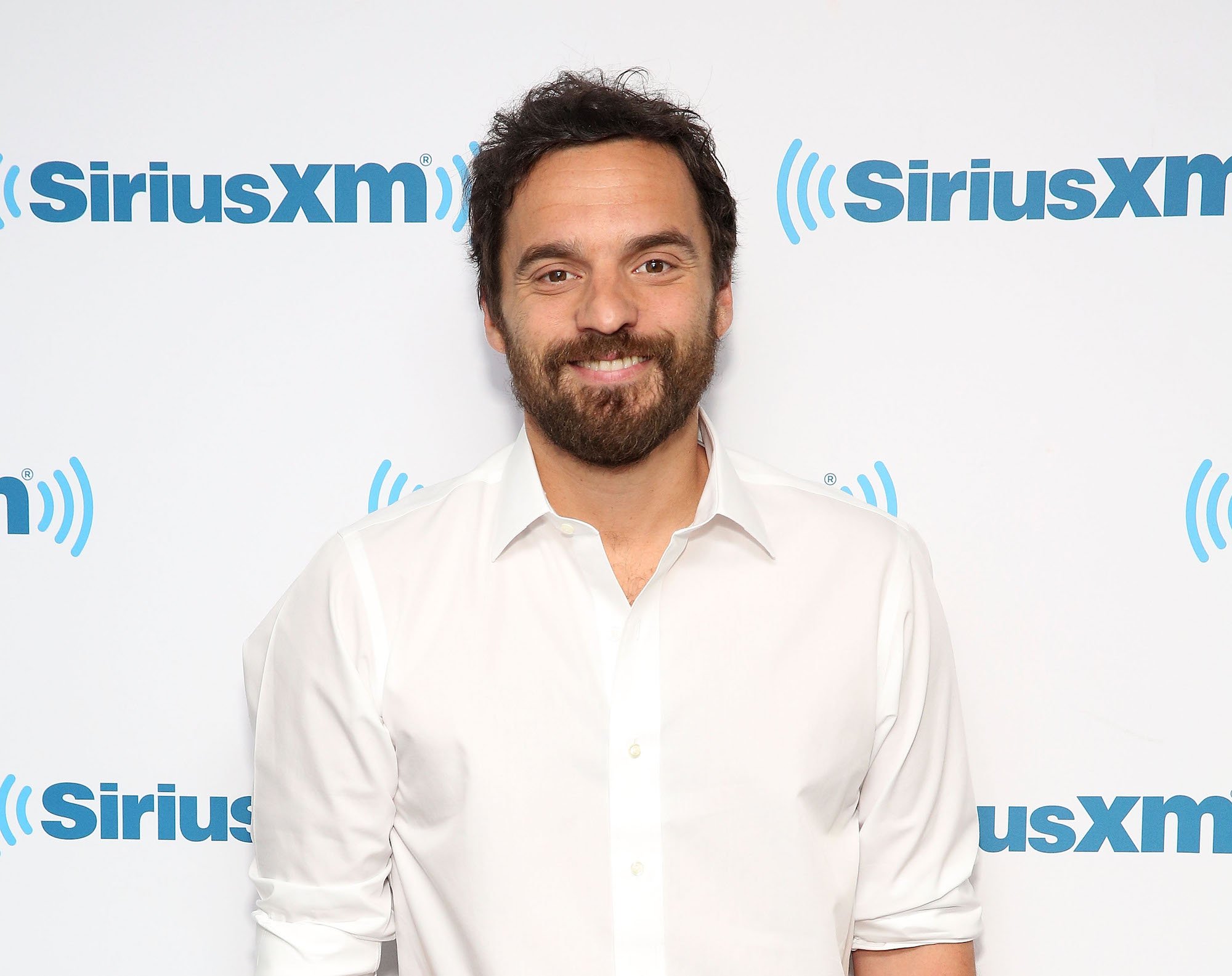 Jake Johnson smiling in front of a white background