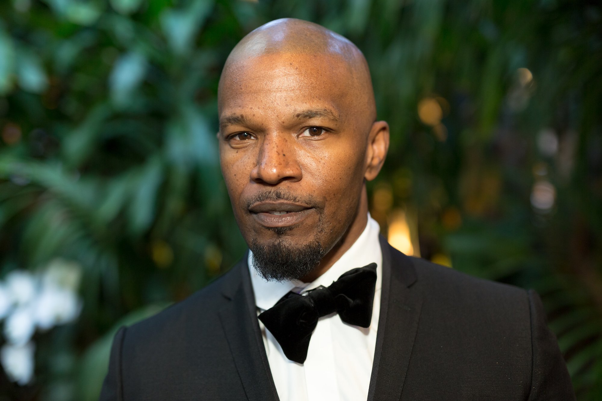 Jamie Foxx slightly smiling in front of a blurred green background