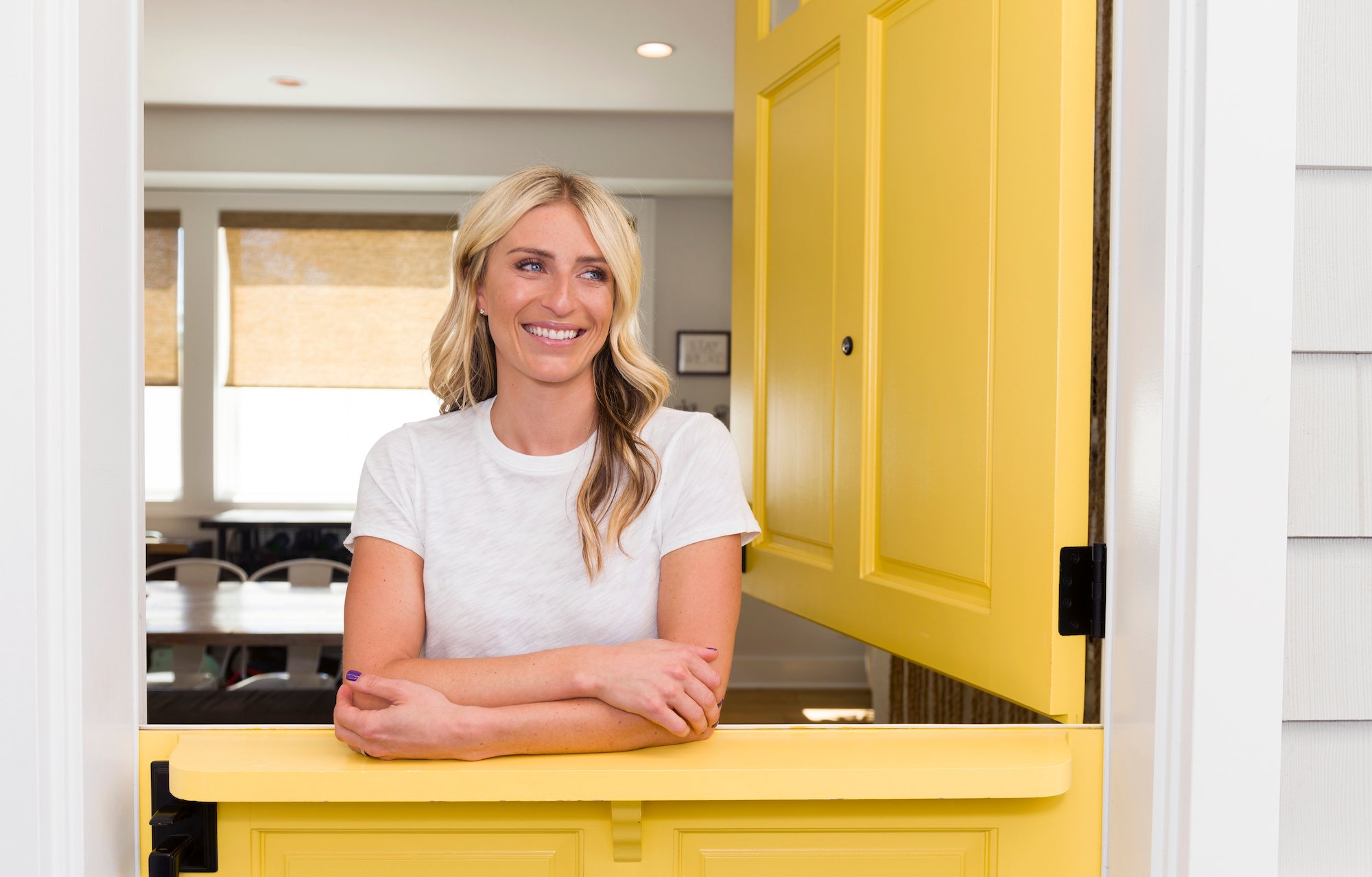 Jasmine Roth smiling leaning against a split yellow door