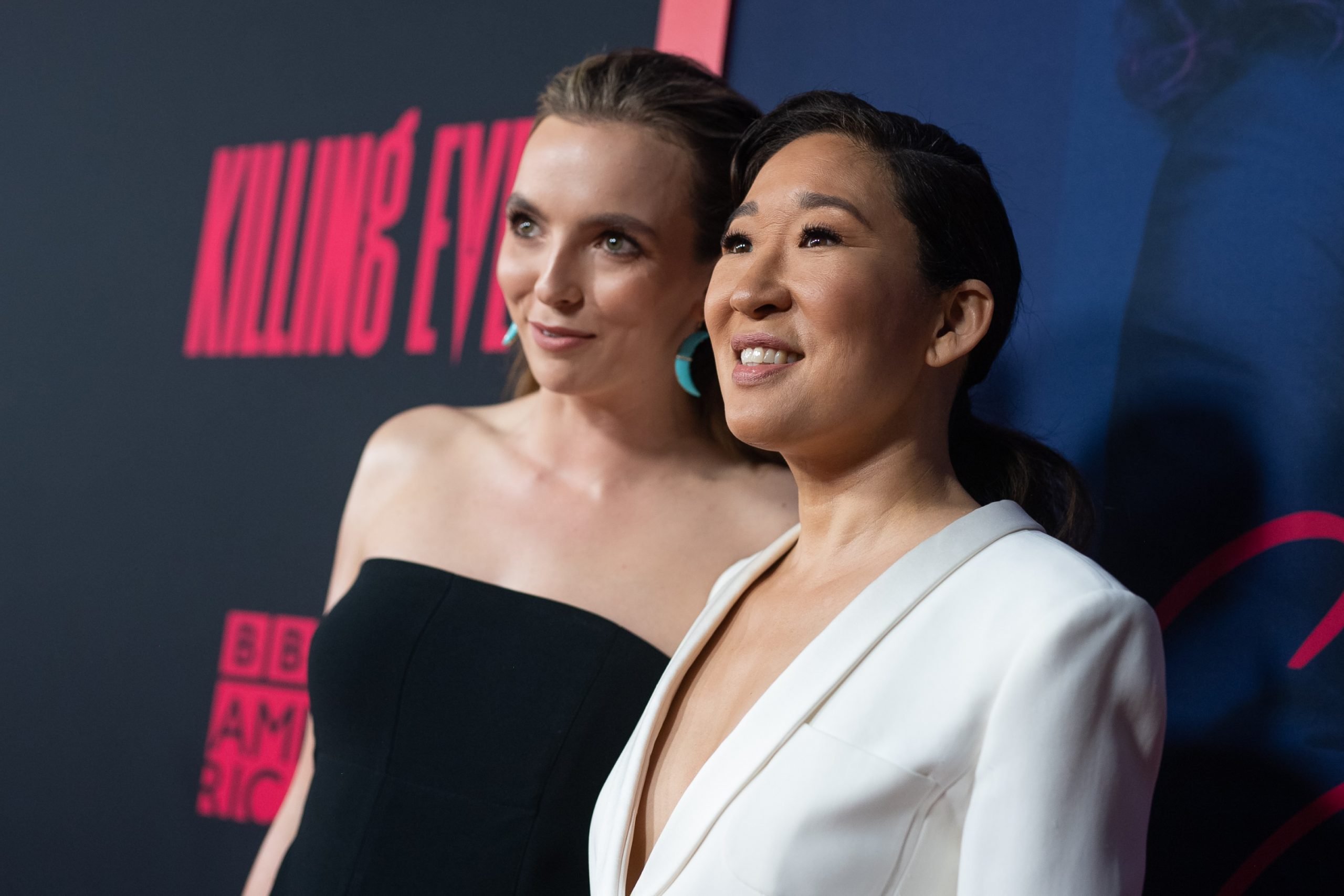 Jodie Comer and Sandra Oh stand next to each other and smile as they pose for photographers at the 'Killing Eve' Season 2 premiere