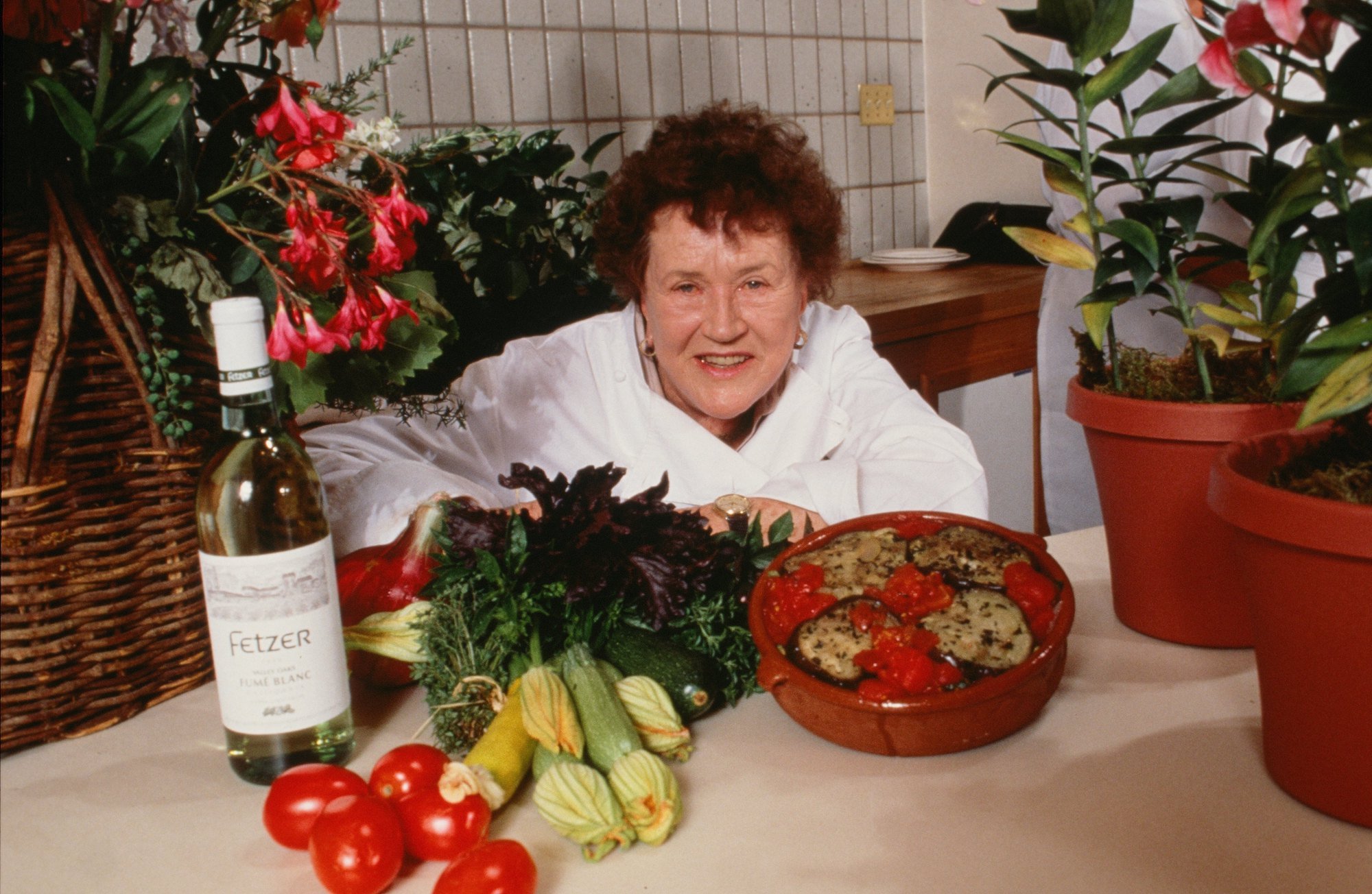 Julia Child smiling behind bowls of food