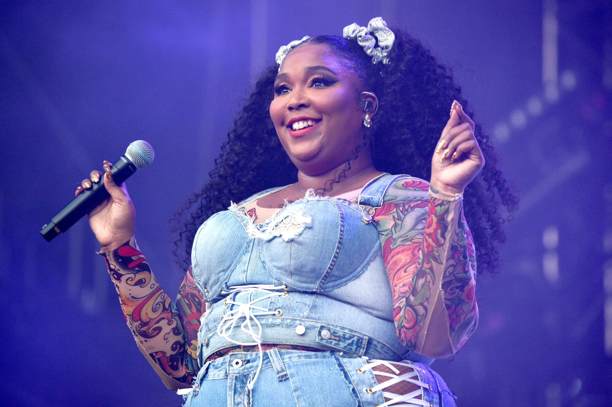 Lizzo smiling, holding a microphone, on stage