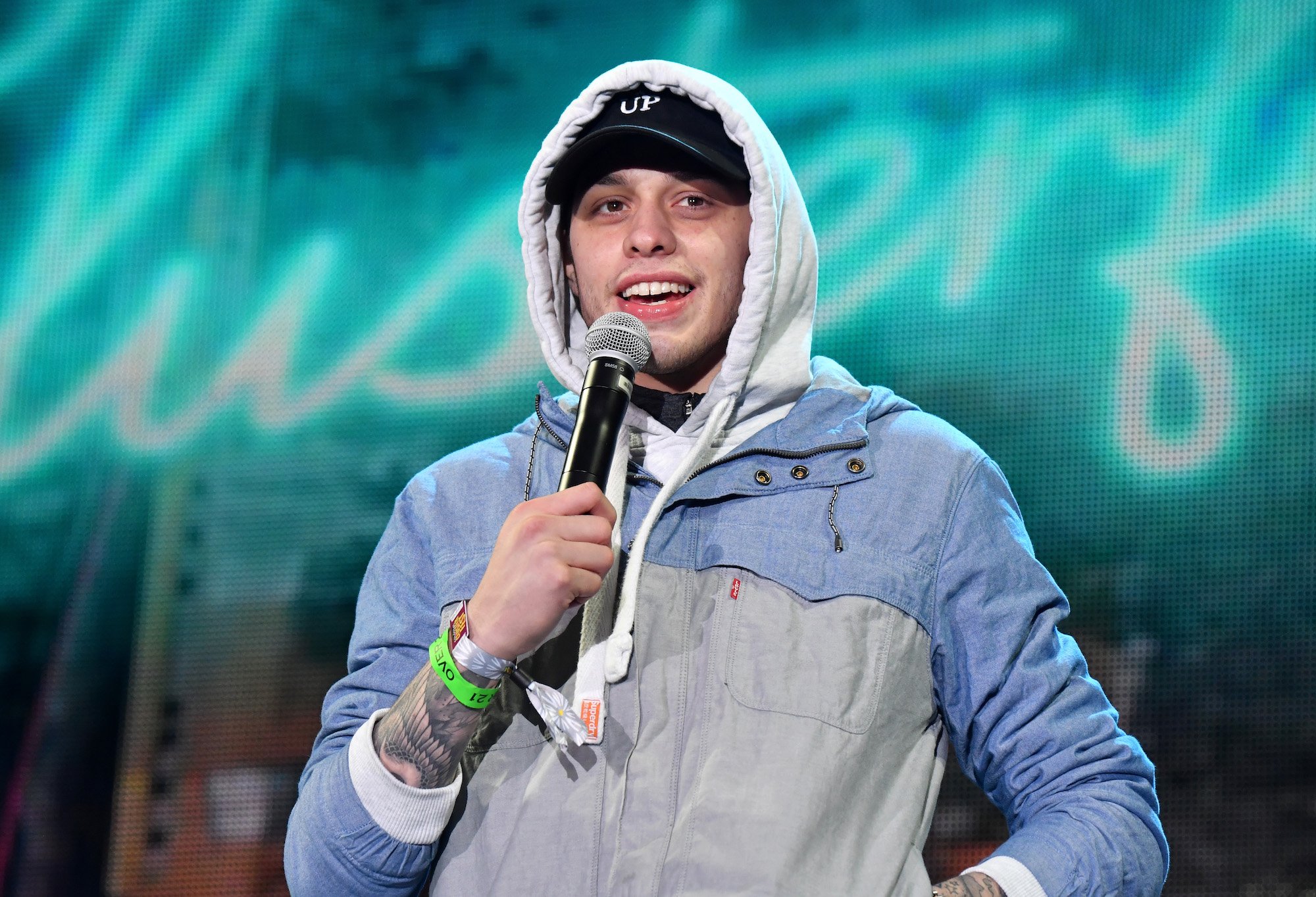 Pete Davidson performing stand up on stage, holding a microphone