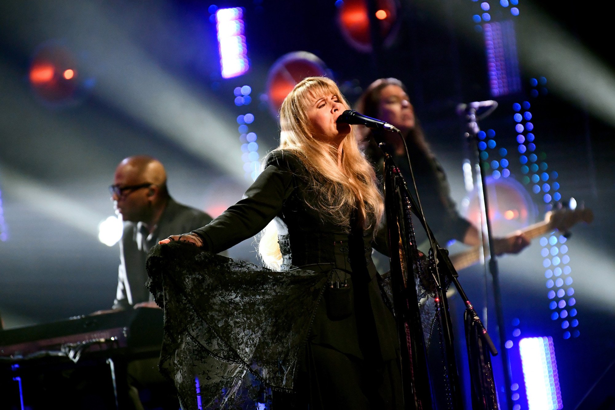 Stevie Nicks singing on stage, arms outstretched