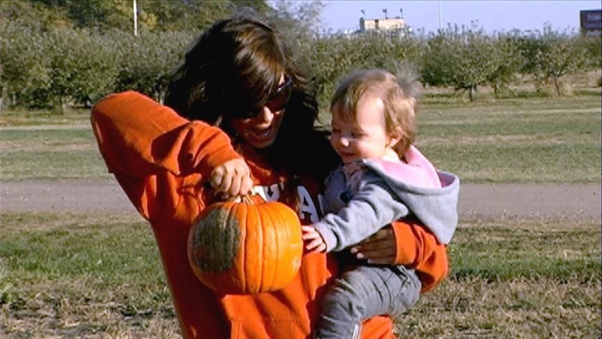 Chelsea Houska and daughter Aubrey smiling, looking at a pumpkin