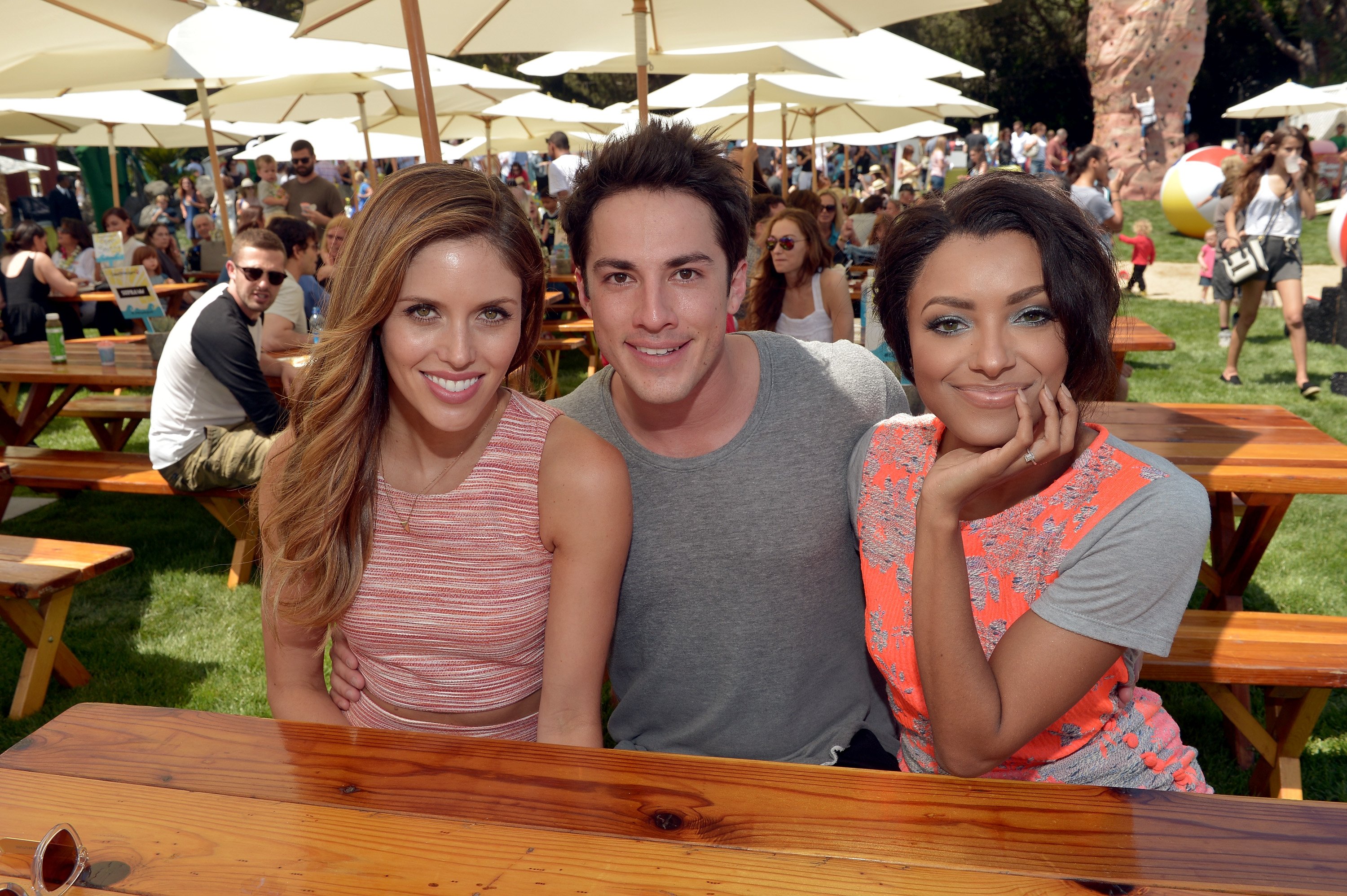 (L-R) Kayla Ewell, Michael Trevino, and Kat Graham smiling at a picnic table