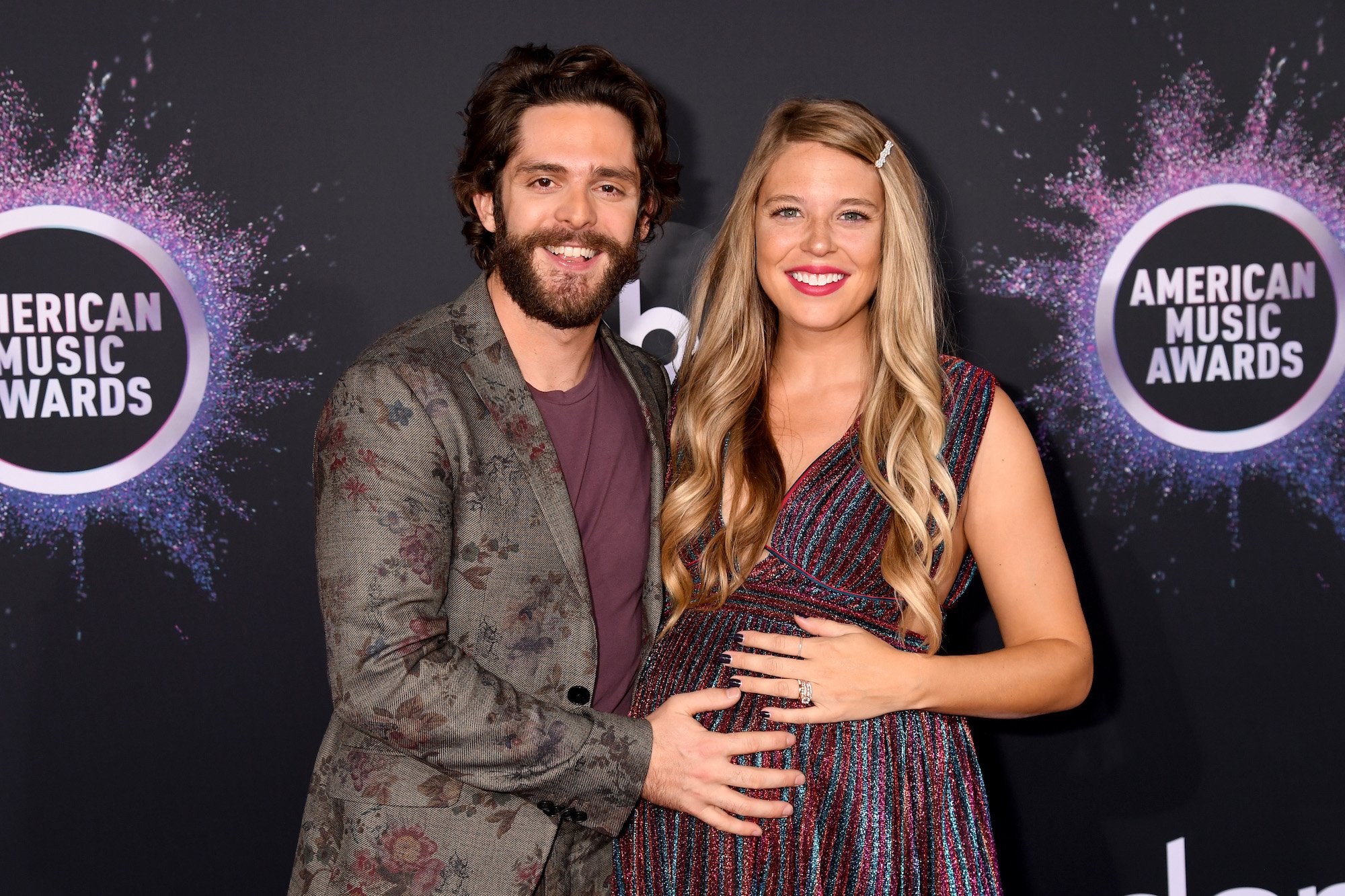 (L-R) Thomas Rhett touching Lauren Akins' pregnant belly smiling