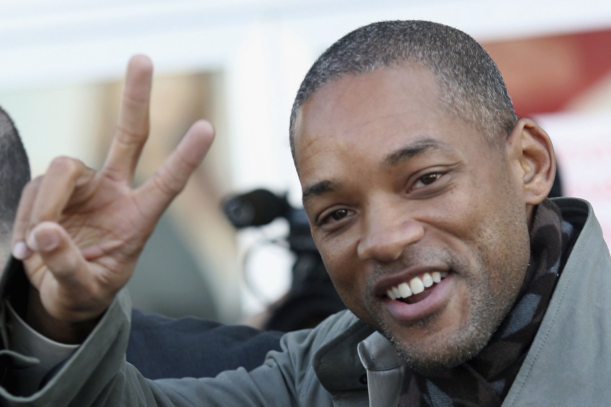 Will Smith smiling, holding up a peace sign