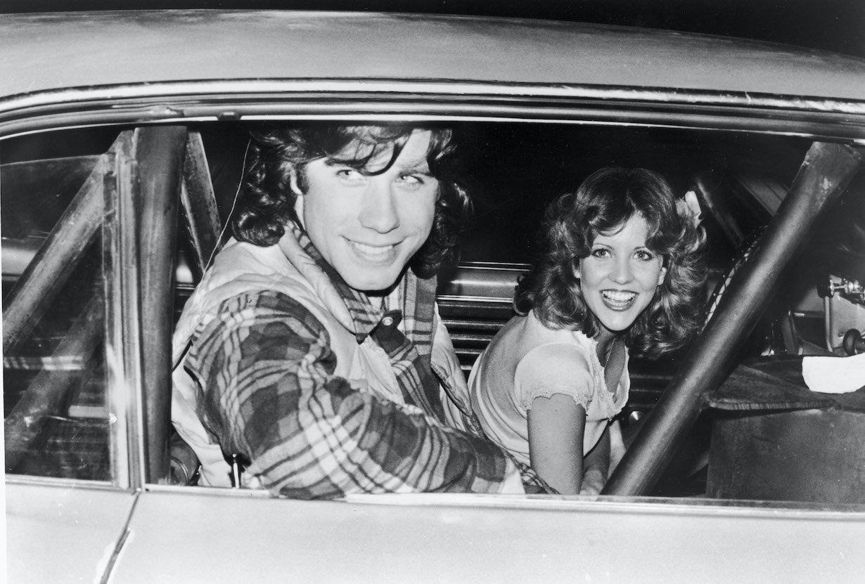 John Travolta and Nancy Allen pose in a car on the set of the film, 'Carrie,' 1976