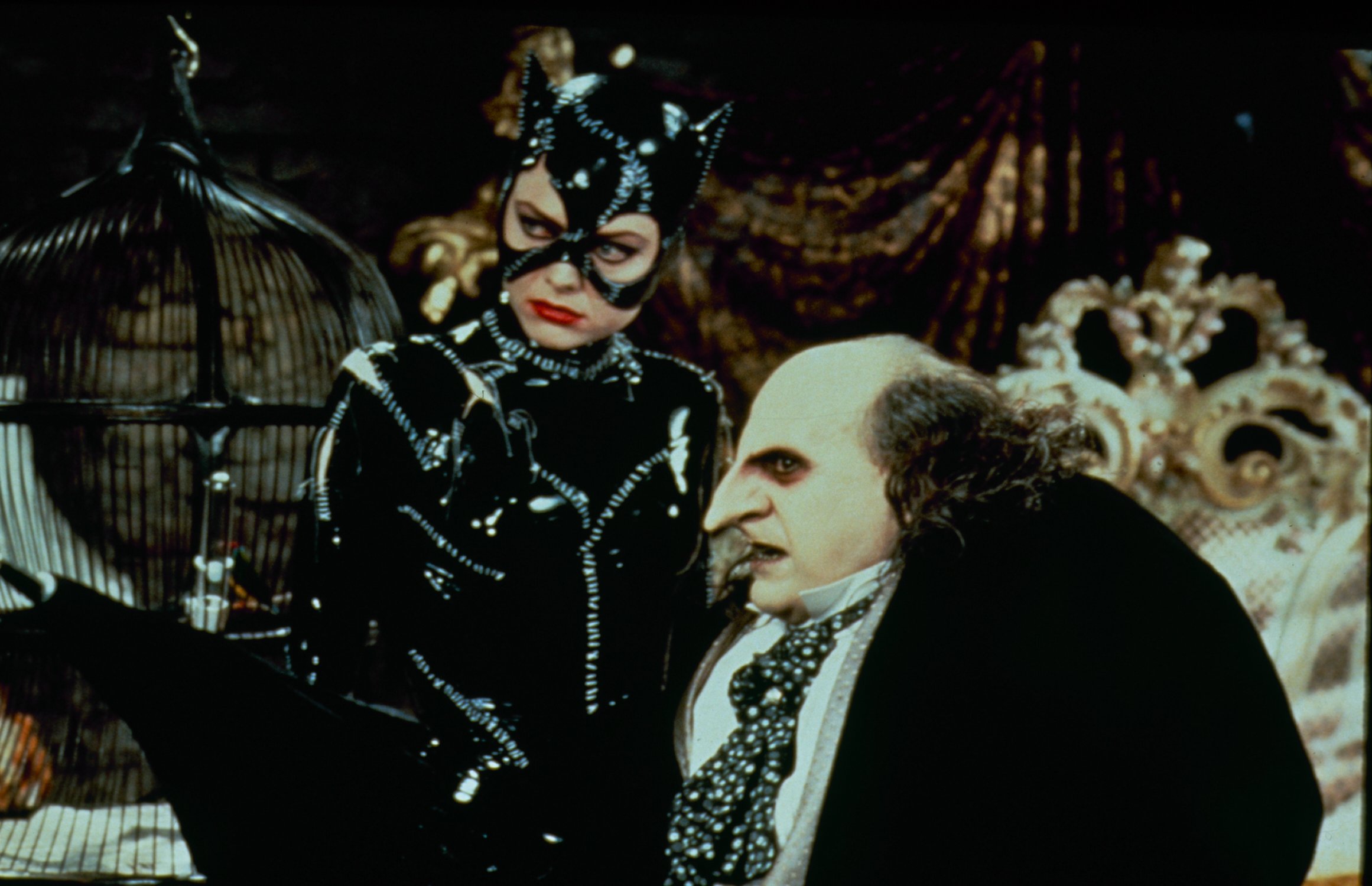 Catwoman and the Penguin near a birdcage