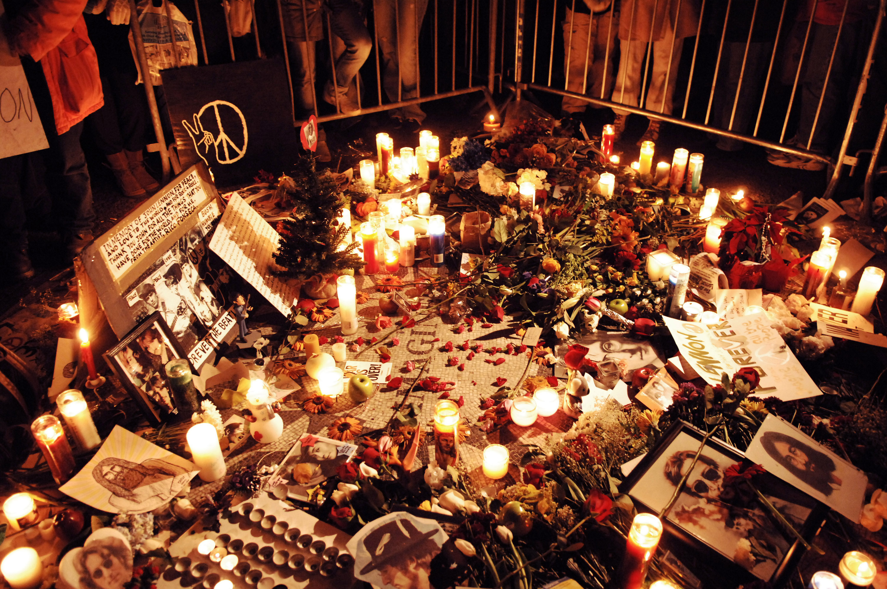 Photos, flowers, and candles at a John Lennon memorial