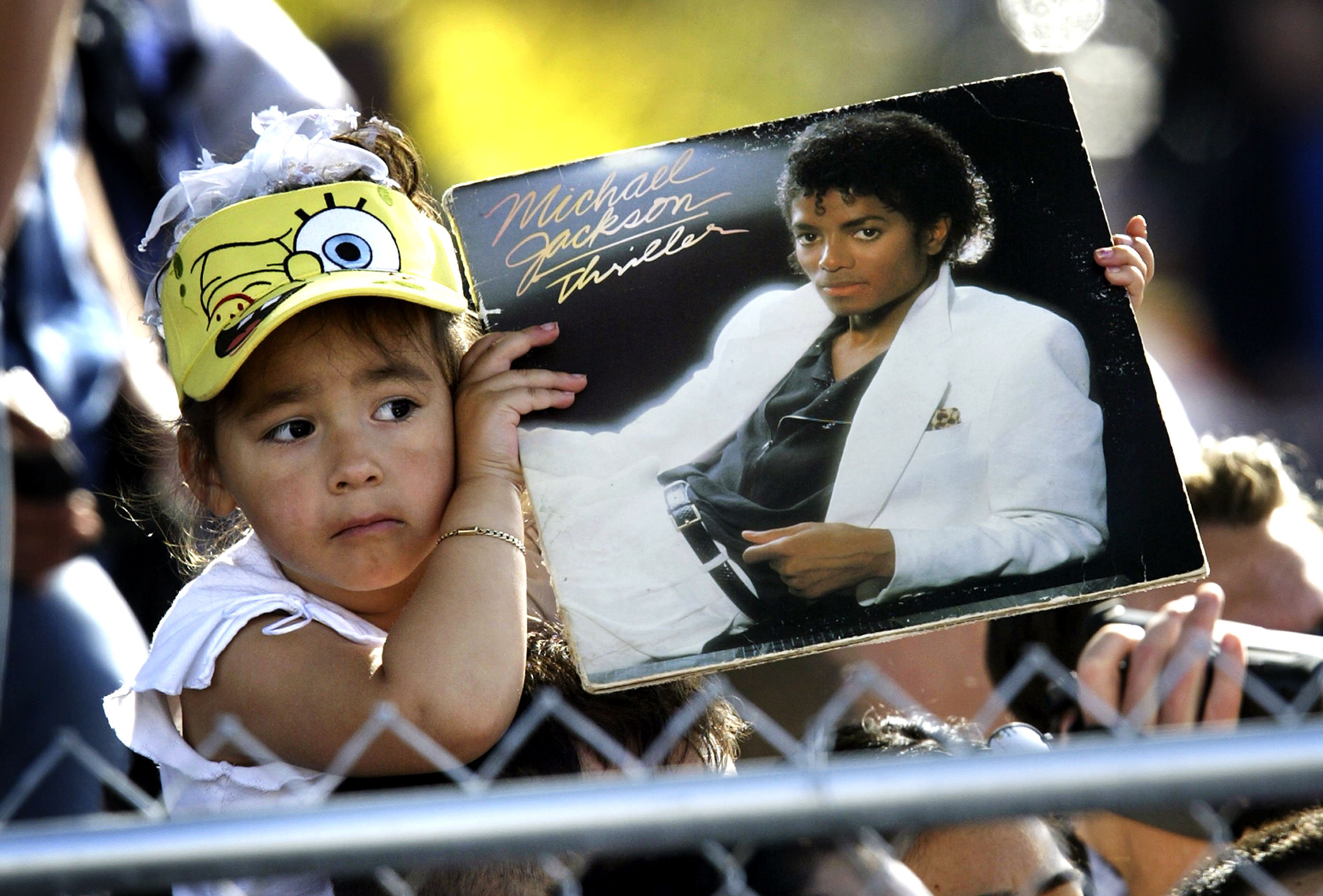 A child wearing a SpongeBob SquarePants hat holding a copy of Thriller
