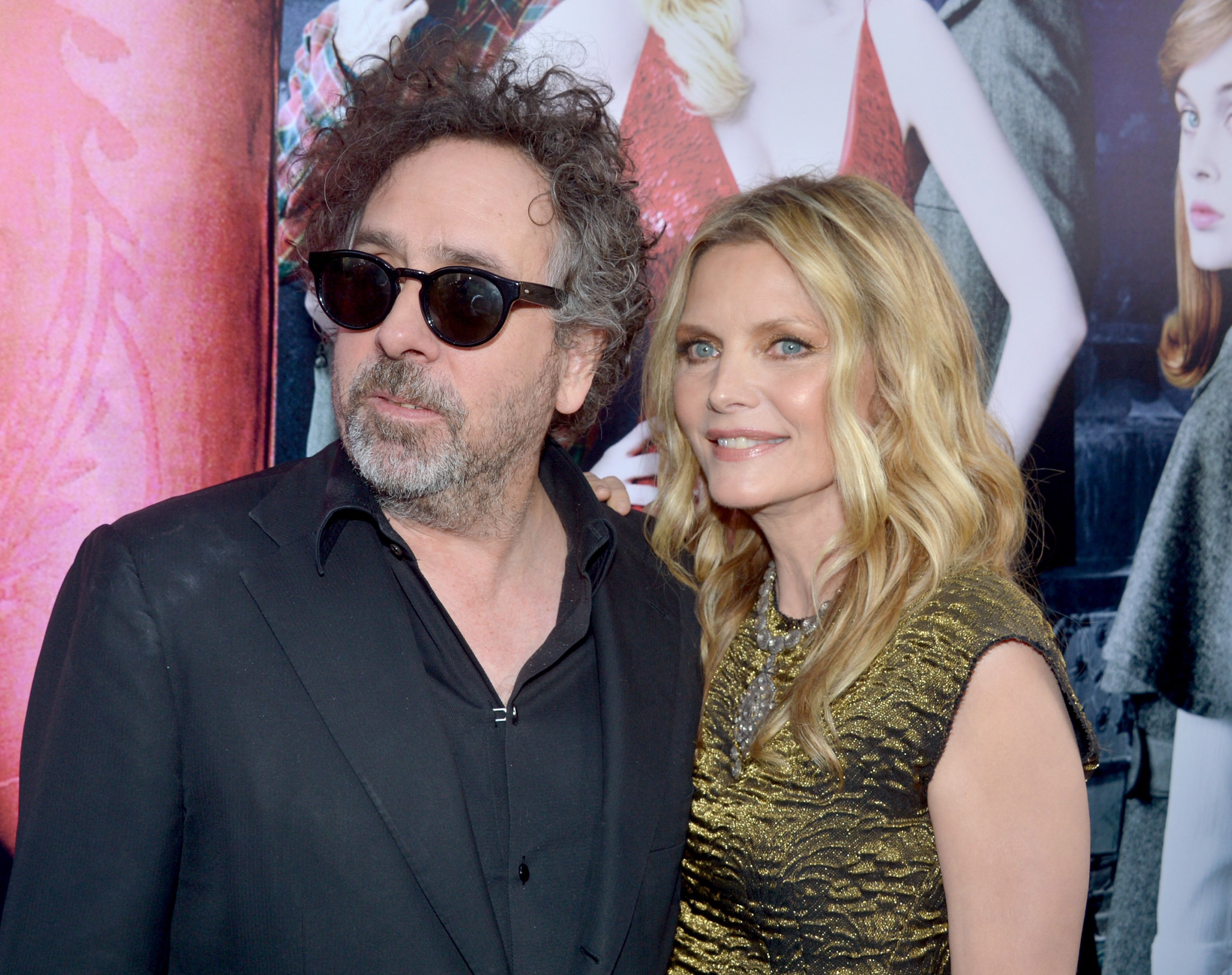 Tim Burton and Michelle Pfeiffer in front of a poster