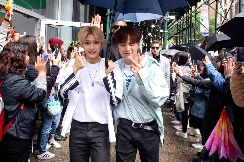 Felix and Woojin of Stray Kids with an umbrella