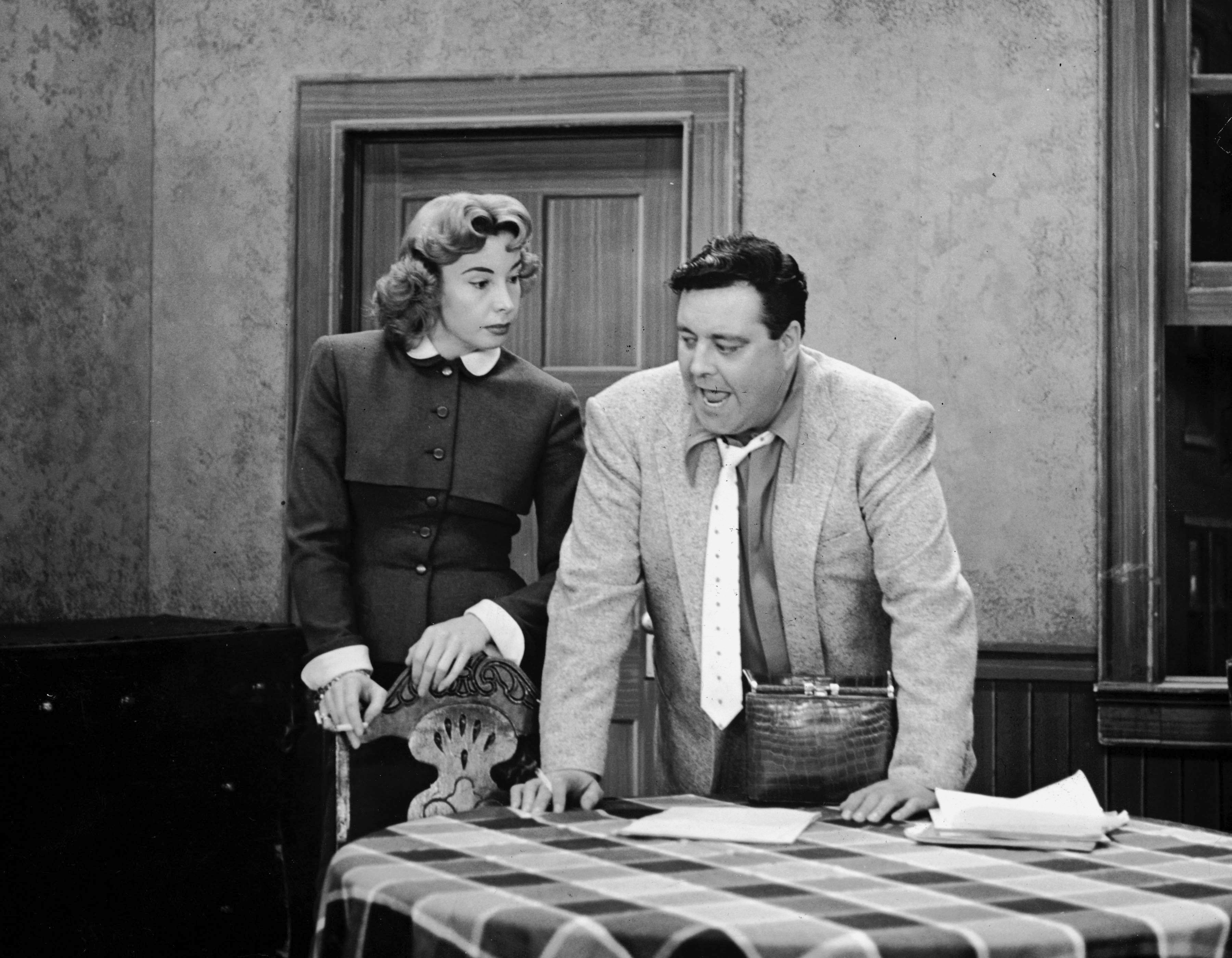Audrey Meadows as Alice Kramden and Jackie Gleason as Ralph Kramden stand in the kitchen on the set of 'The Honeymooners' 