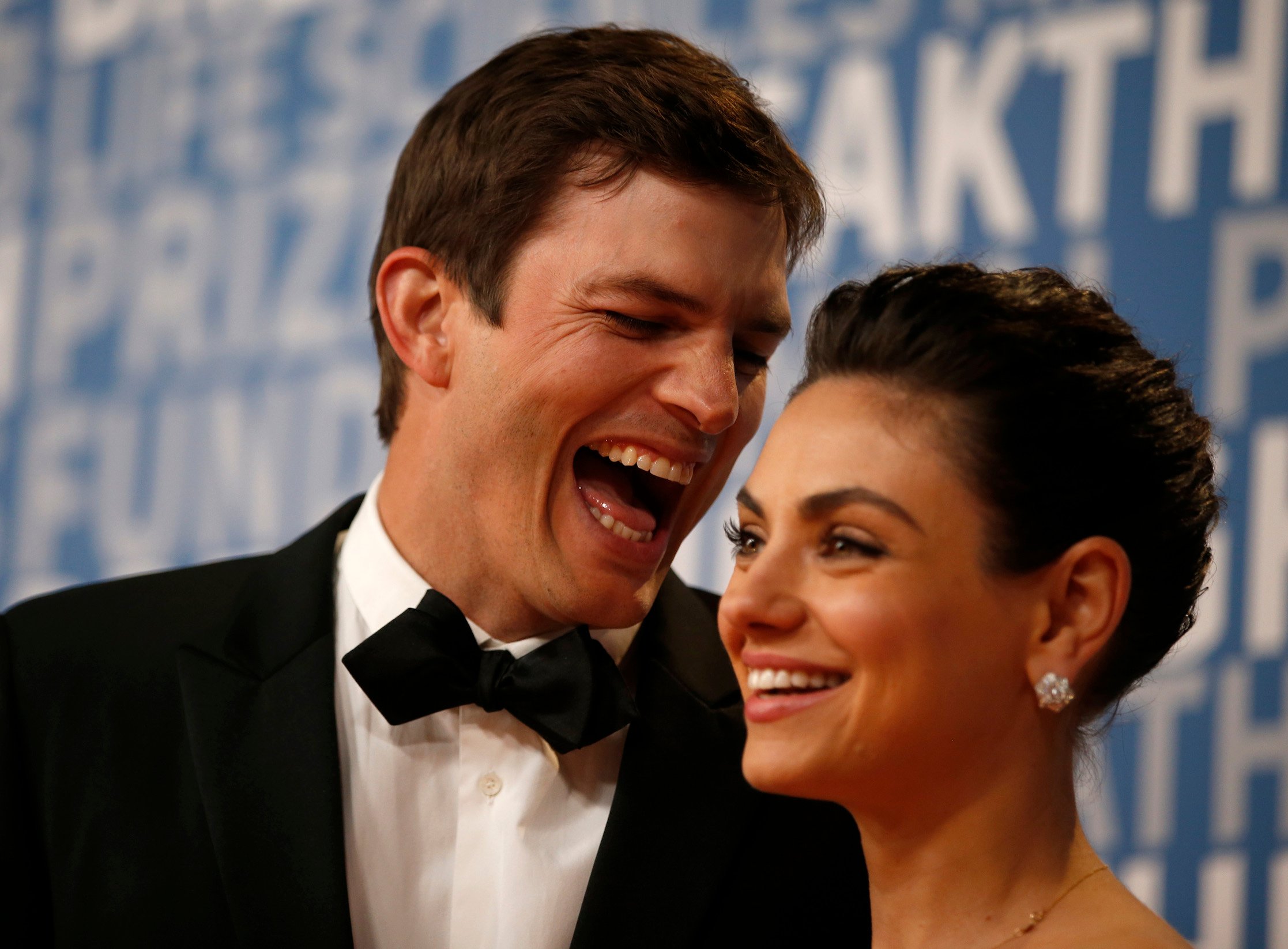Ashton Kutcher laughs with his wife, actor Mila Kunis