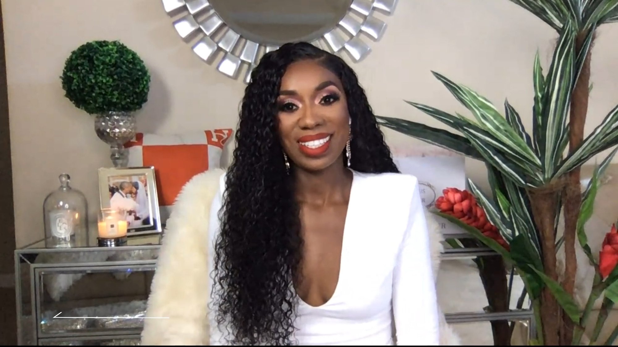 Dr. Wendy Osefo smiling in front of a mirror and plant, in a screen grab from 'Watch What Happens Live With Andy Cohen'