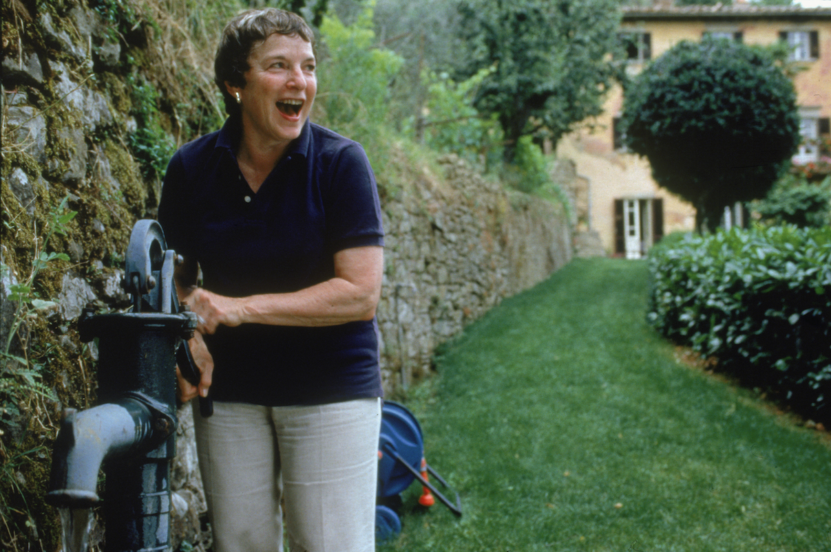 Frances Mayes at her own Tuscan villa drawing water from an outdoor hand-pump well