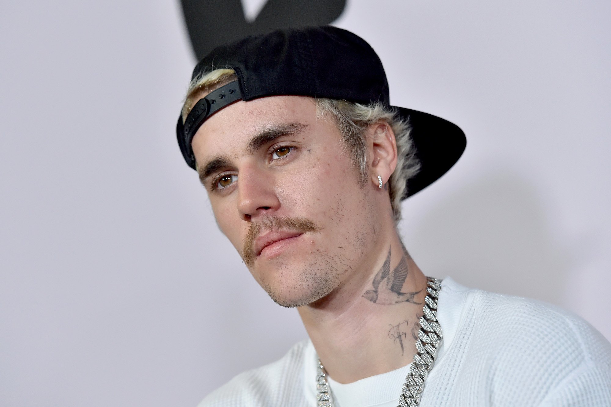 Justin Bieber looking toward the left, standing in front of a white background