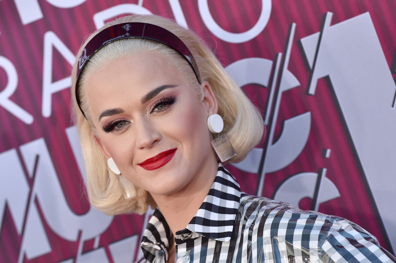 Katy Perry smiling in front of a purple background