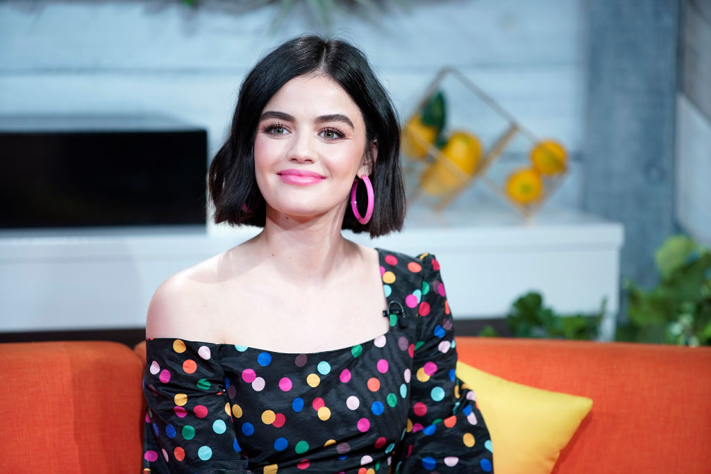 Lucy Hale smiling, sitting on an orange couch