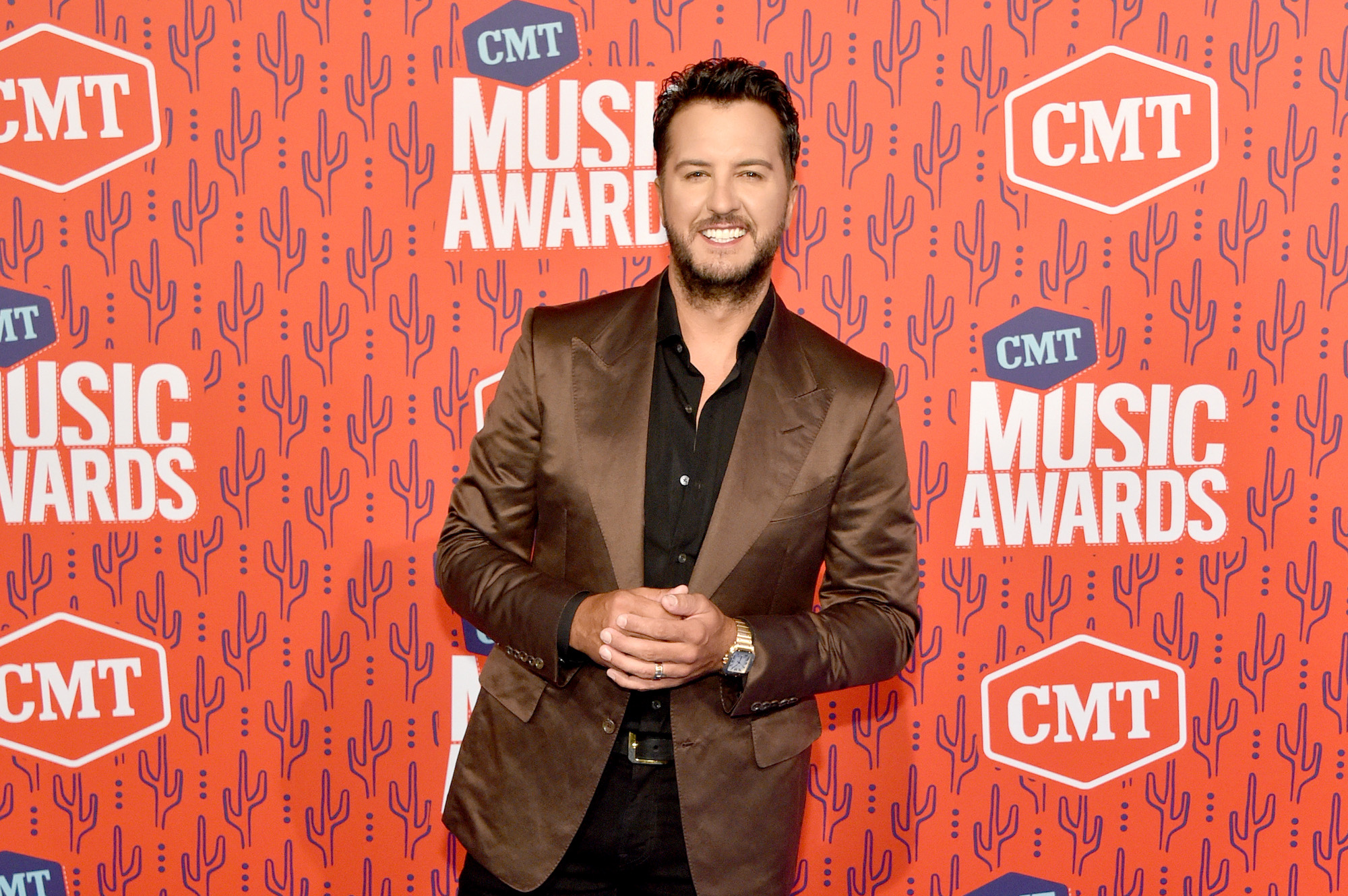 Luke Bryan smiling in front of an orange background