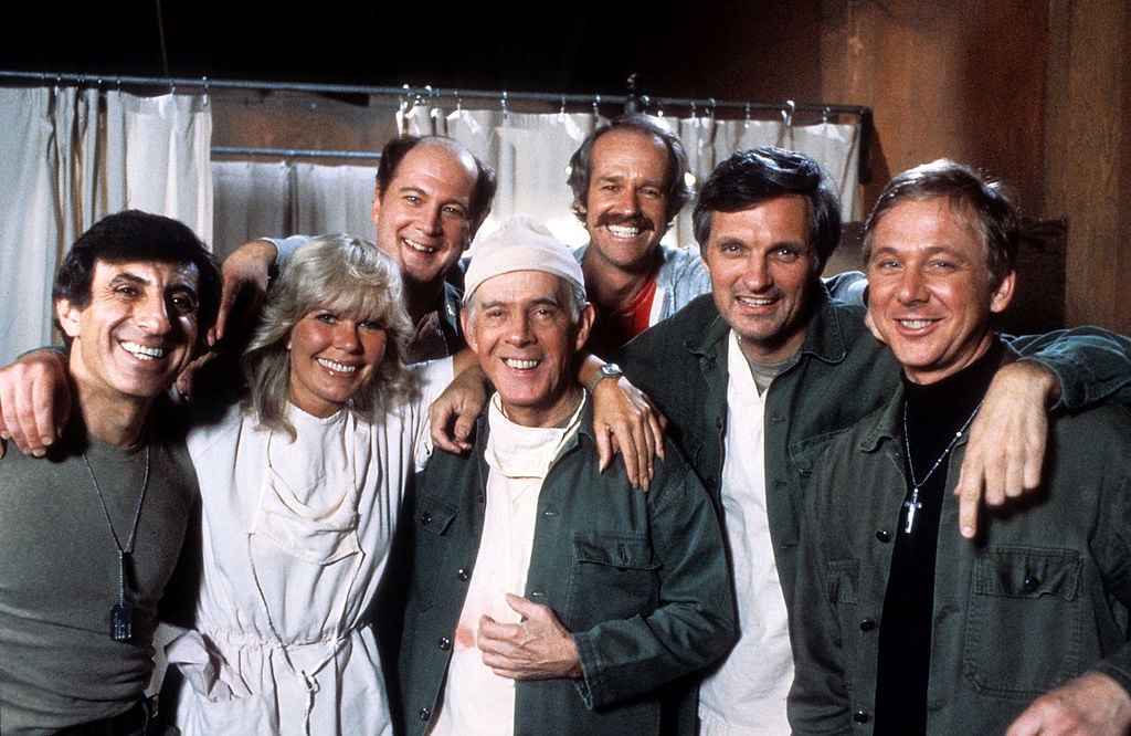 (L-R) Jamie Farr, Loretta Swit, David Ogden Stiers, Harry Morgan, Mike Farrell, Alan Alda, and William Christopher smiling