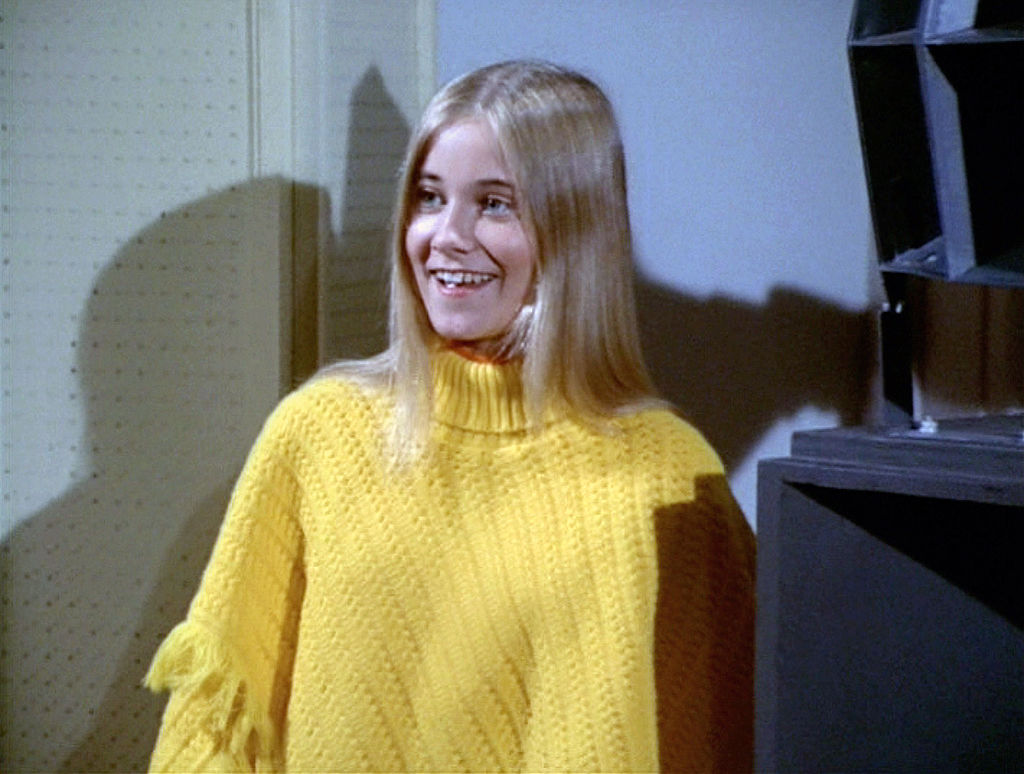Maureen McCormick as Marcia Brady smiling, wearing a yellow sweater