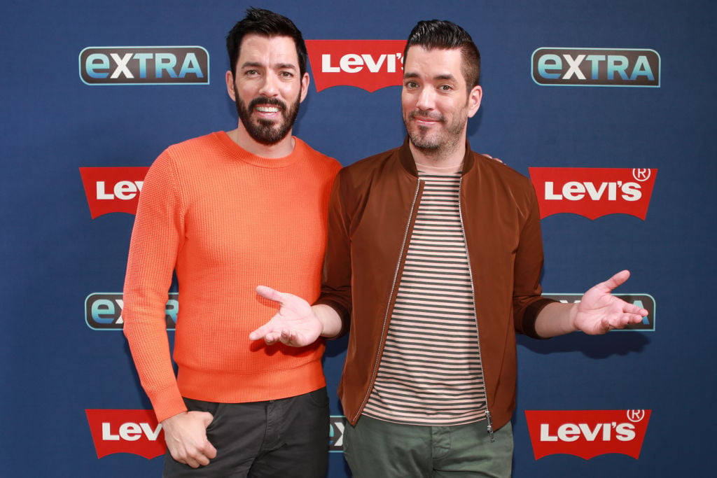(L-R) Drew Scott and Jonathan Scott smiling in front of a blue background