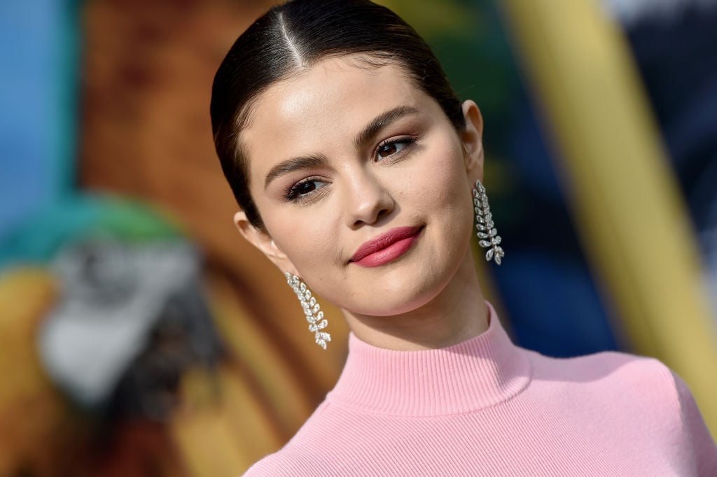 Selena Gomez smiling in front of a blurred background