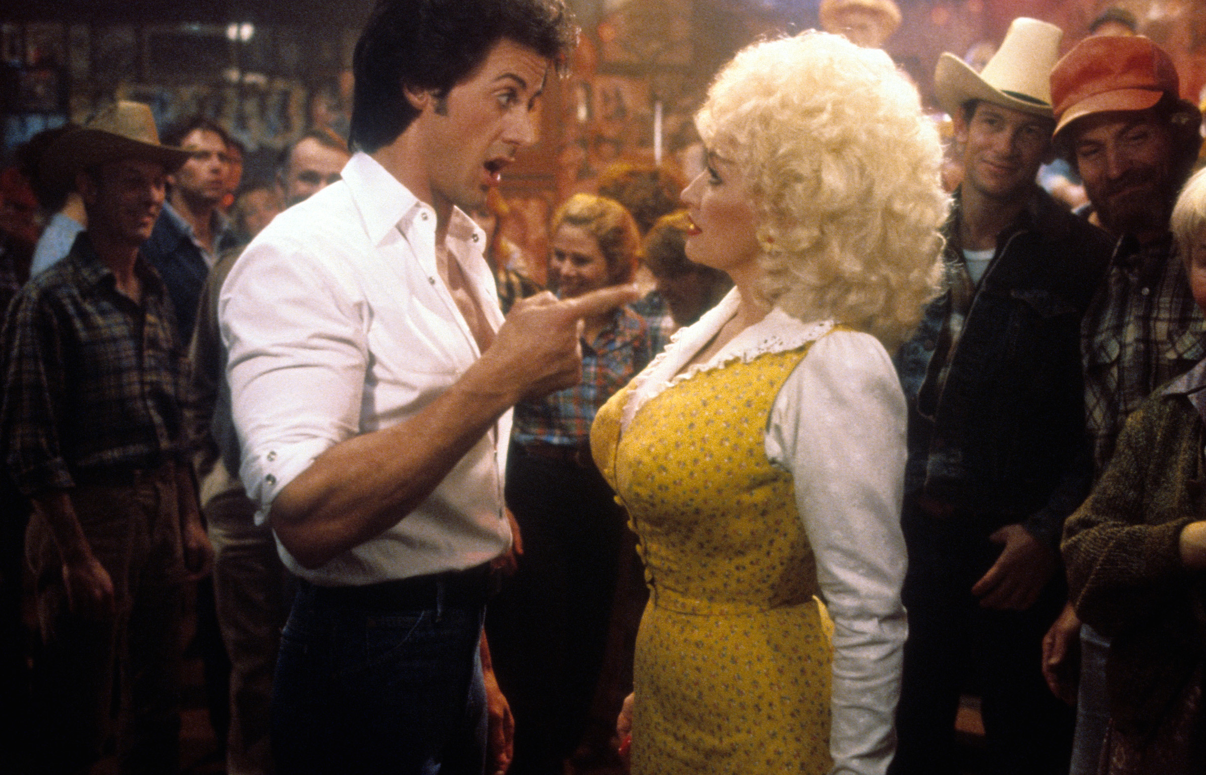 Sylvester Stallone points to Dolly Parton in a scene from the film 'Rhinestone' 