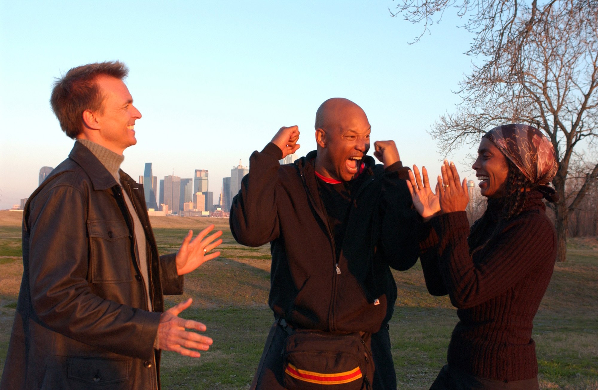 Chip (center) and Kim McAllister (left) celebrate after crossing the finish line with Phil Keoghan beside them on 'The Amazing Race'