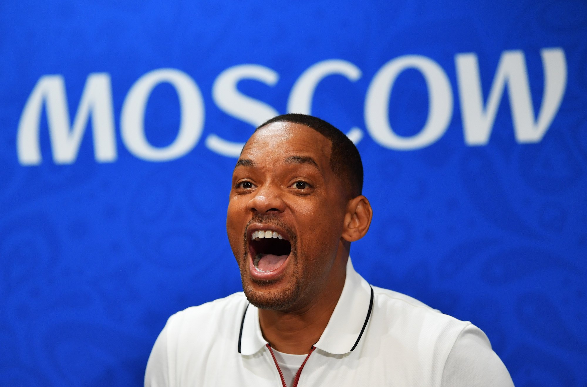 Will Smith with his jaw dropped, looking surprised, in front of a blue background