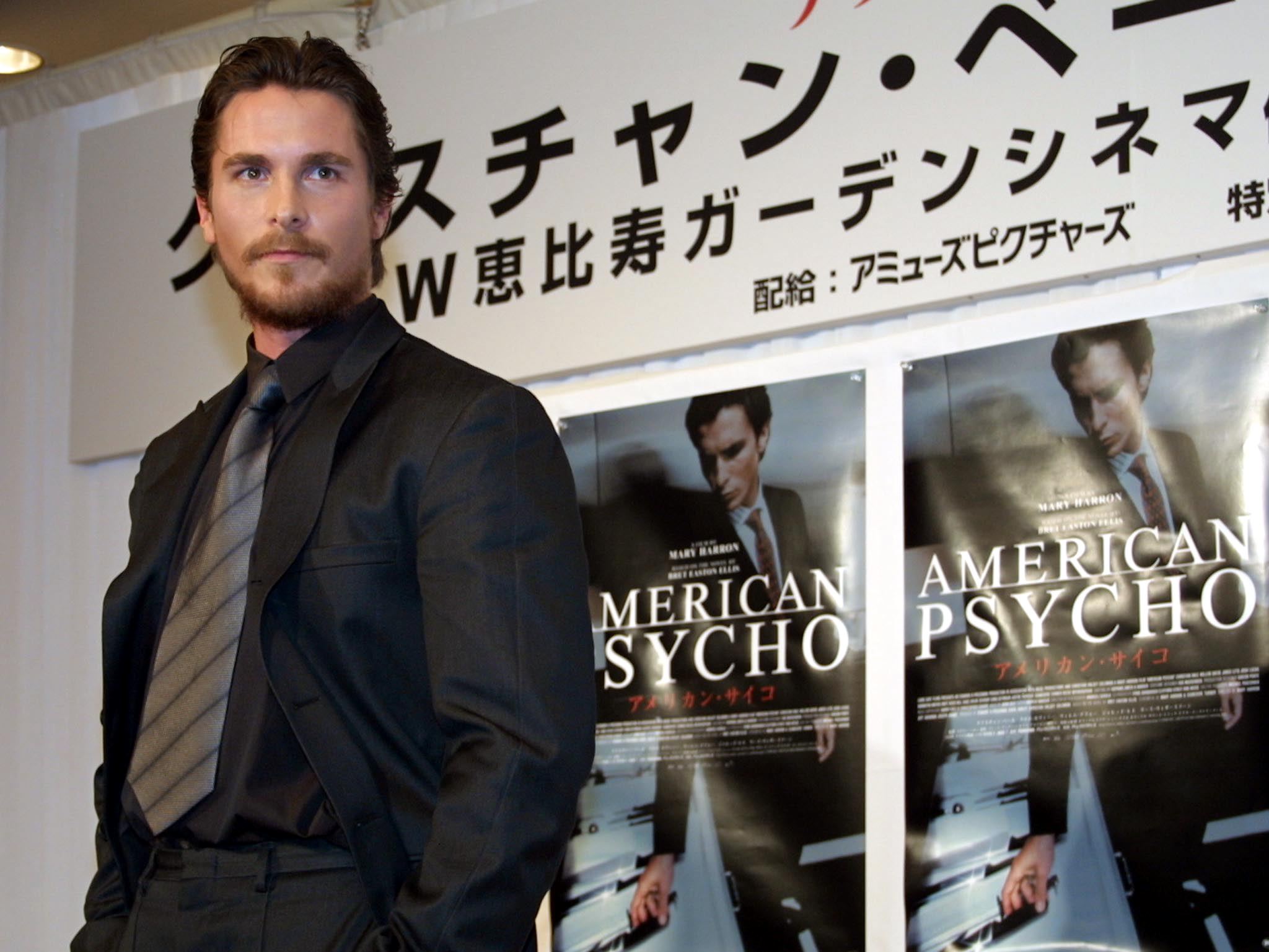 Christian Bale near posters for American Psycho