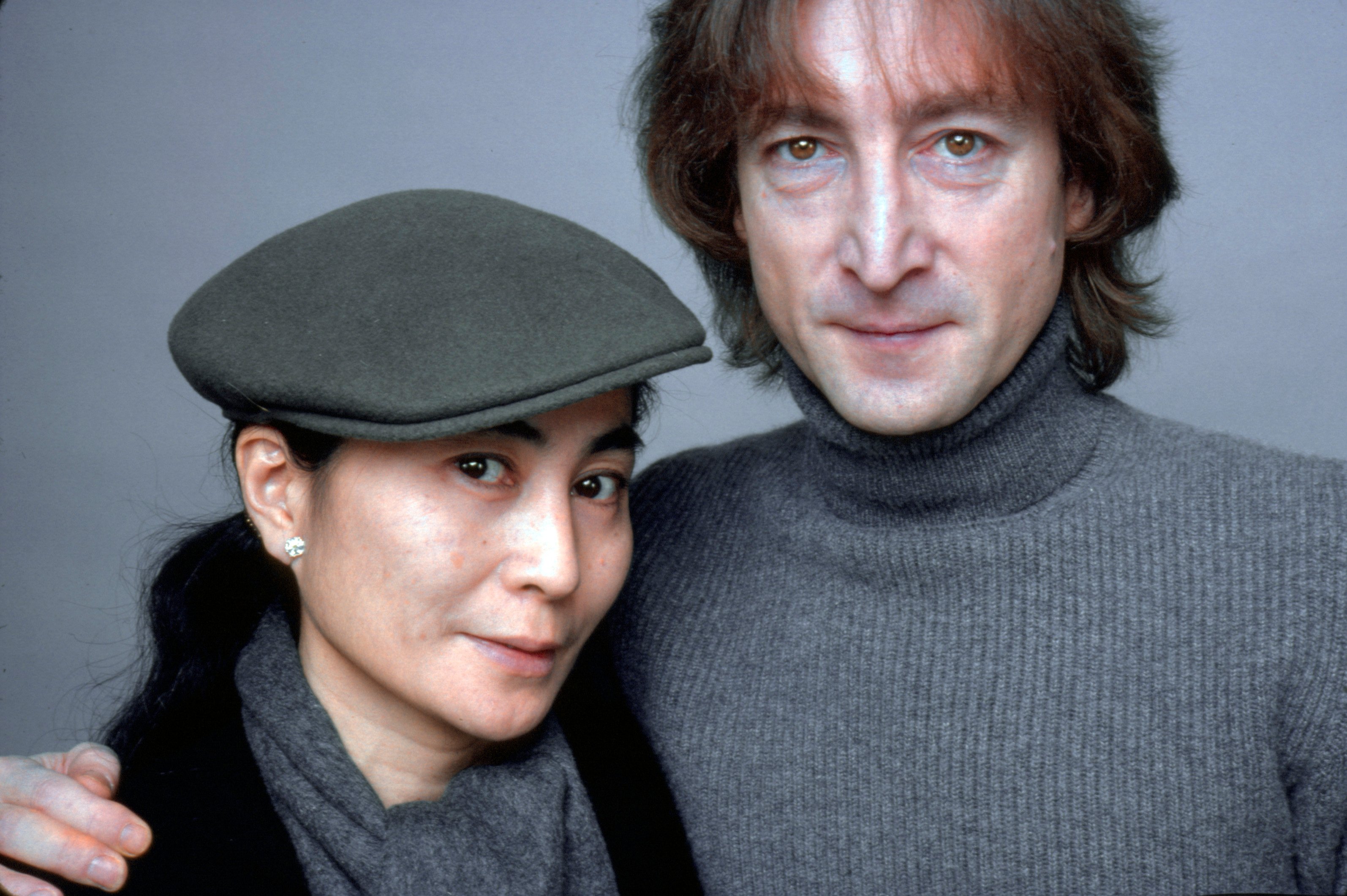Yoko Ono wearing a beret and standing next to John Lennon