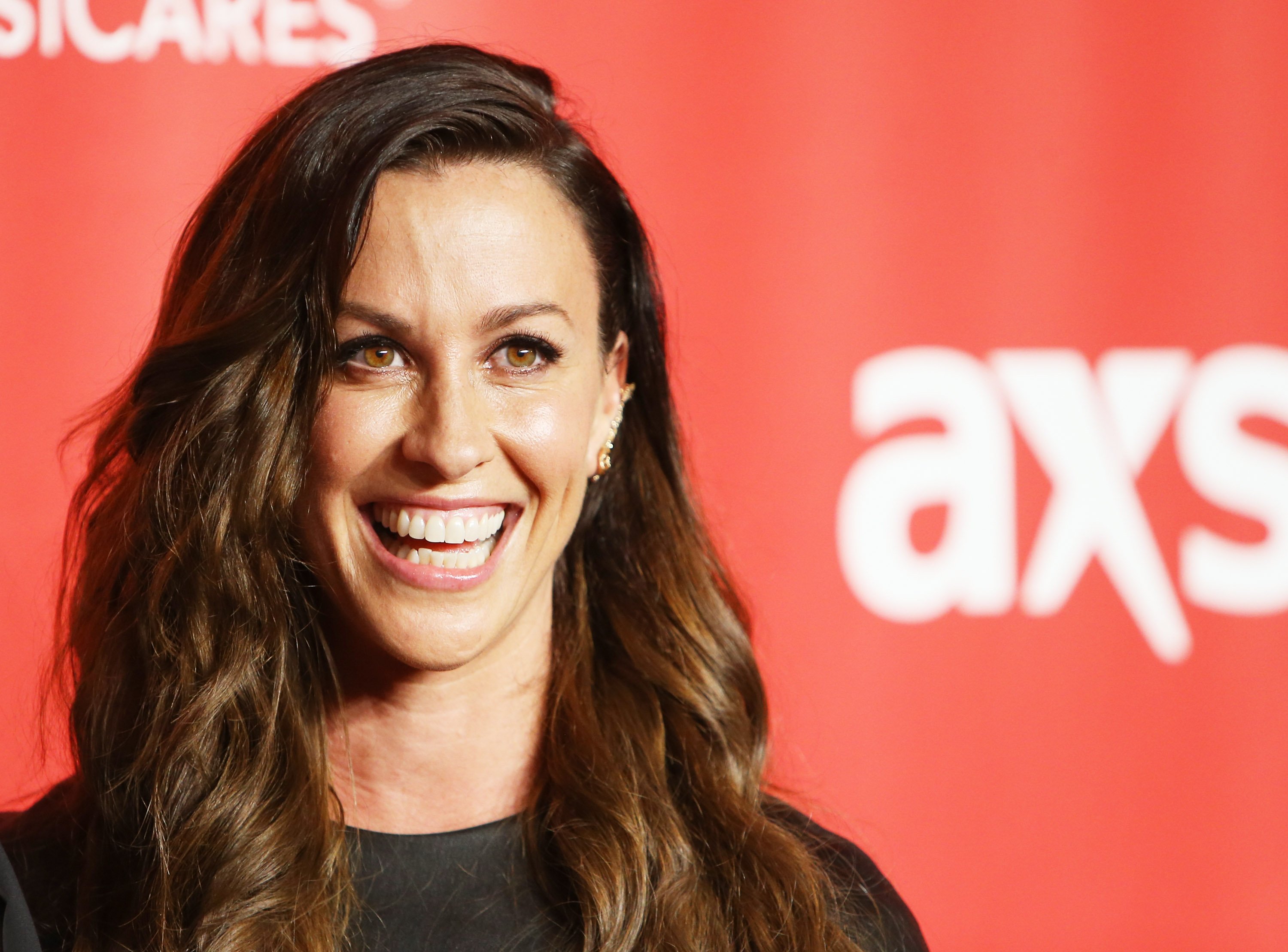 Alanis Morissette smiles for a photo on the red carpet
