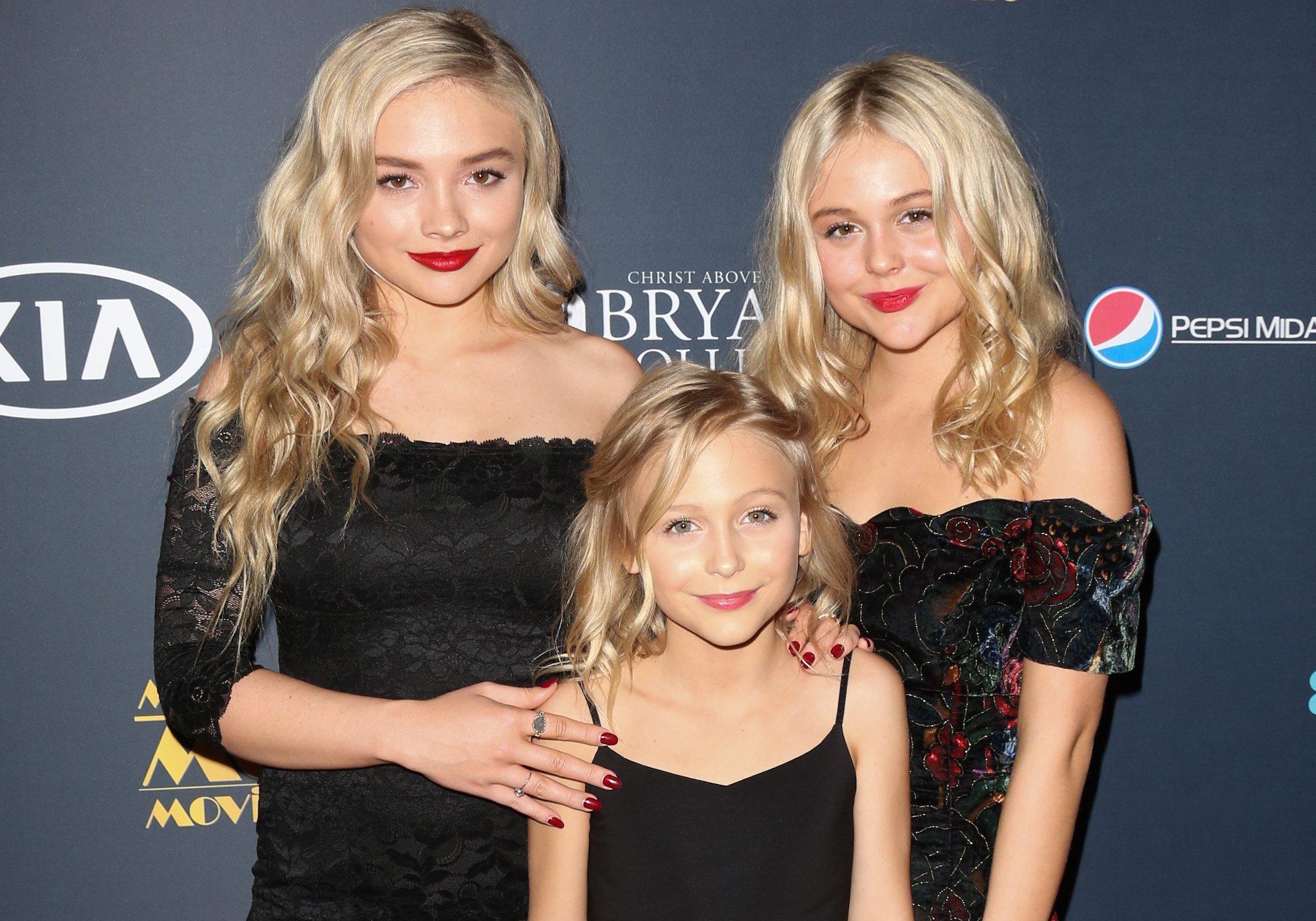 (L-R) Natalie Alyn Lind, Alyvia Alyn Lind and Emily Alyn Lind smiling in front of a black background