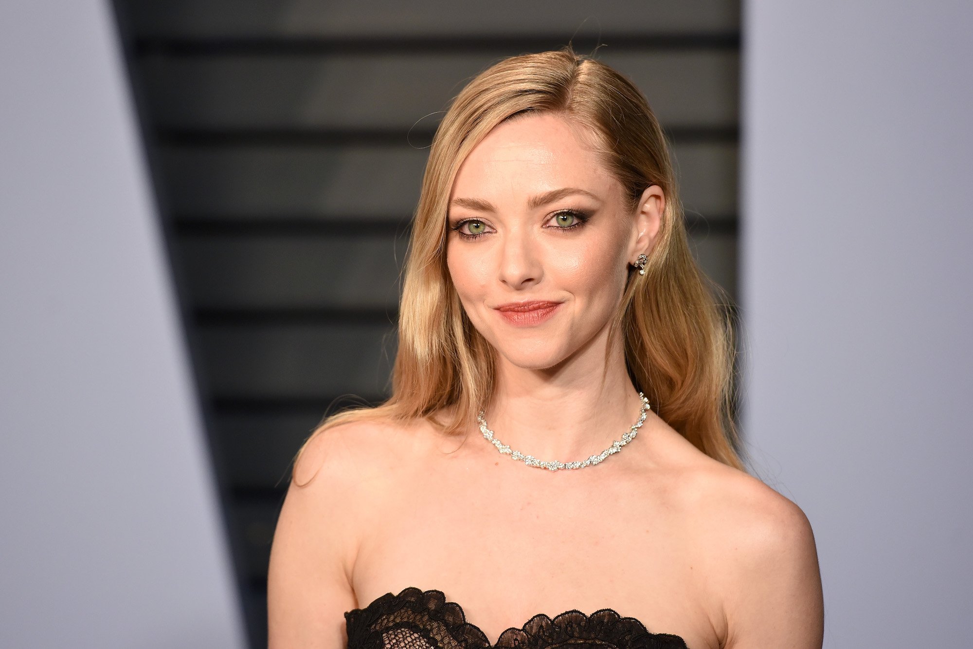 Amanda Seyfried smiling in front of a gray background