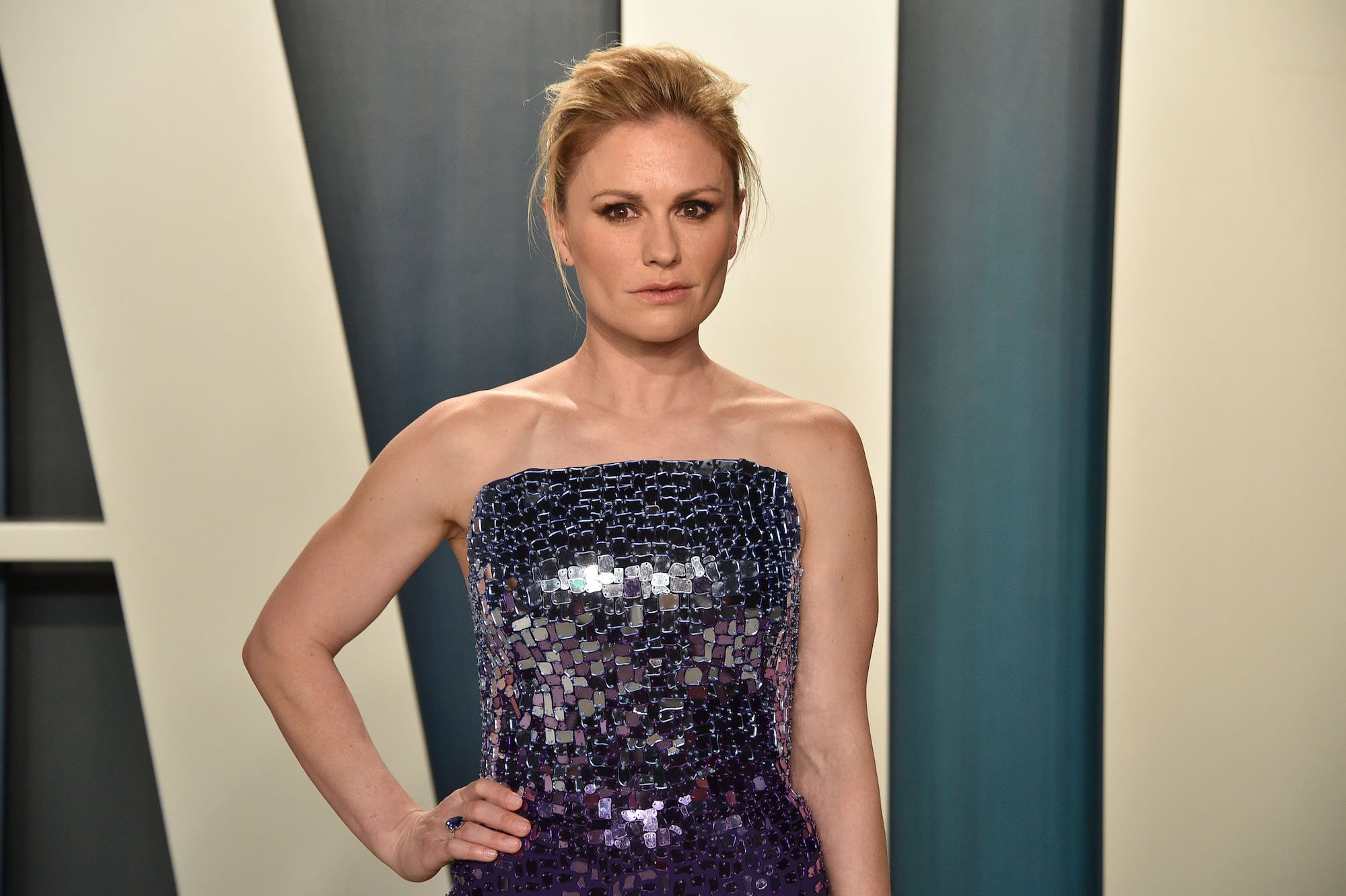Anna Paquin smiling slightly in front of a blue background