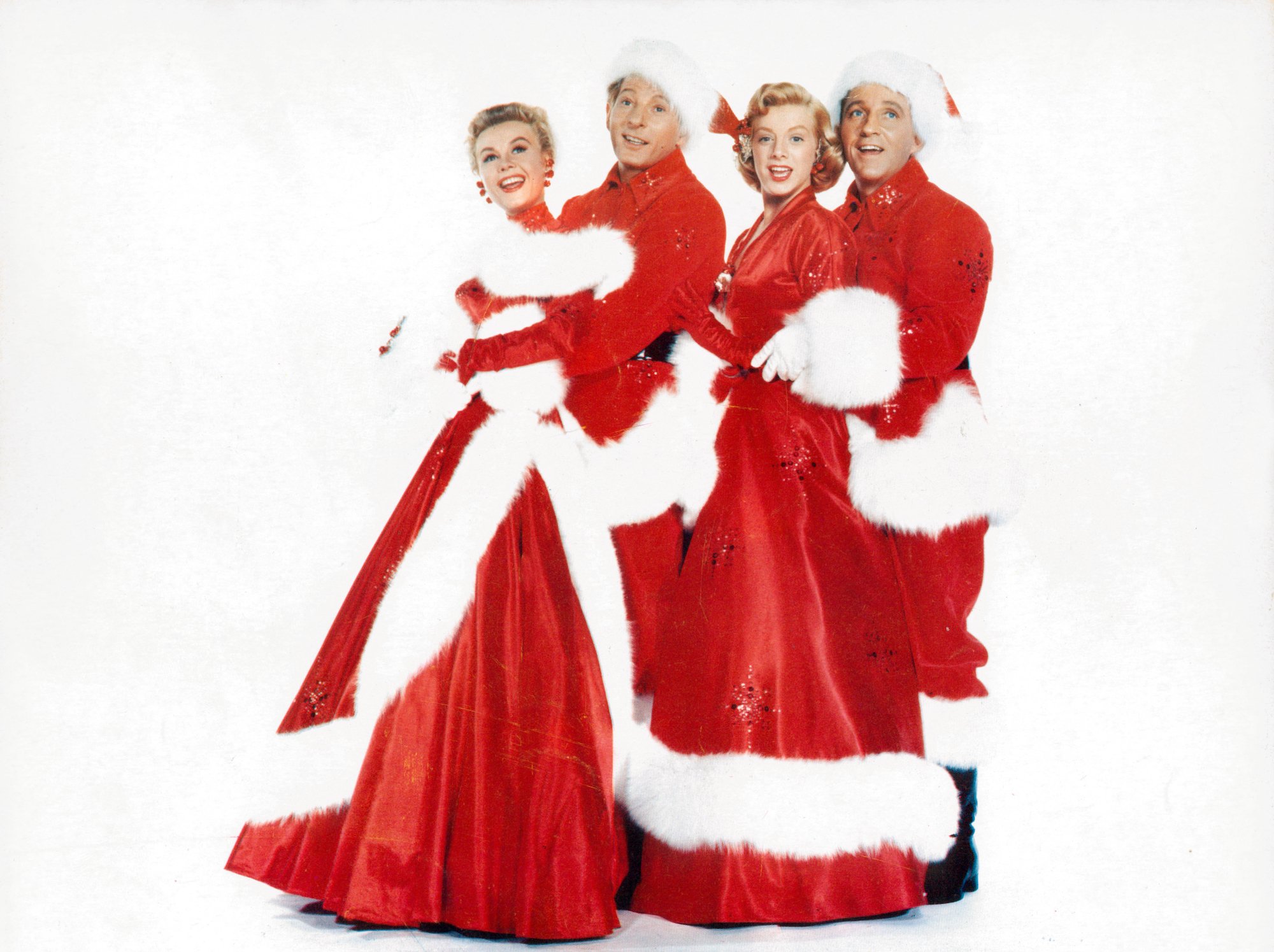 (L-R) Vera-Ellen, Danny Kaye, Rosemary Clooney, and Bing Crosby smiling in front of a white background in Christmas stage costumes