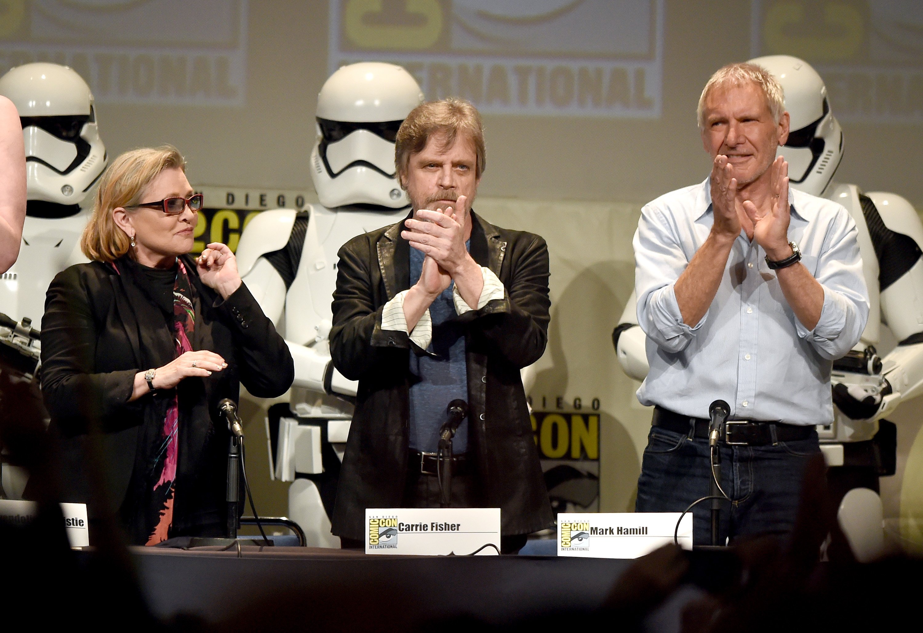 Actors Carrie Fisher, Mark Hamill and Harrison Ford applaud onstage at the Lucasfilm panel during Comic-Con International 2015 at the San Diego Convention Center on July 10, 2015 in San Diego, California.