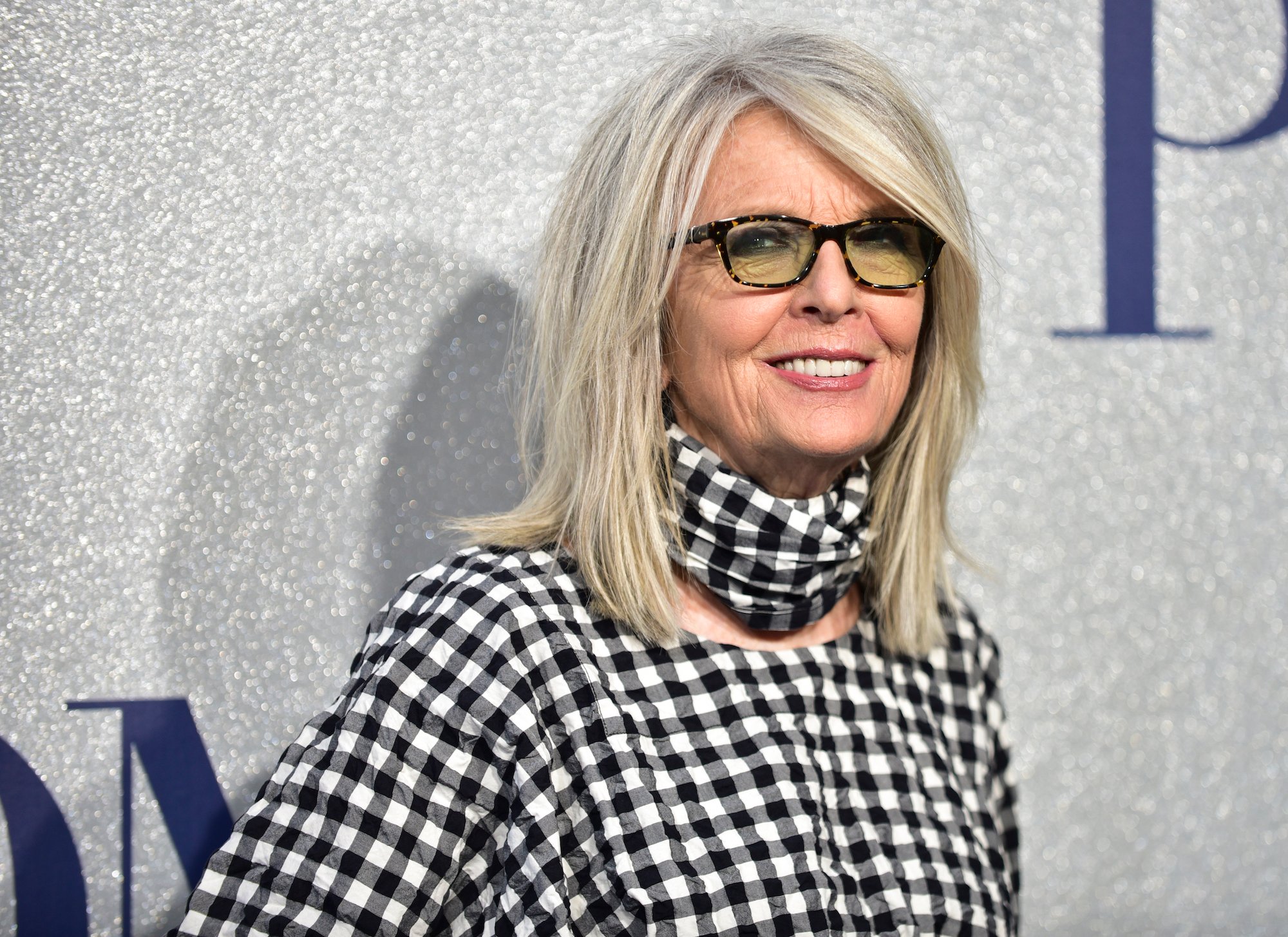 Diane Keaton smiling in front of a gray background