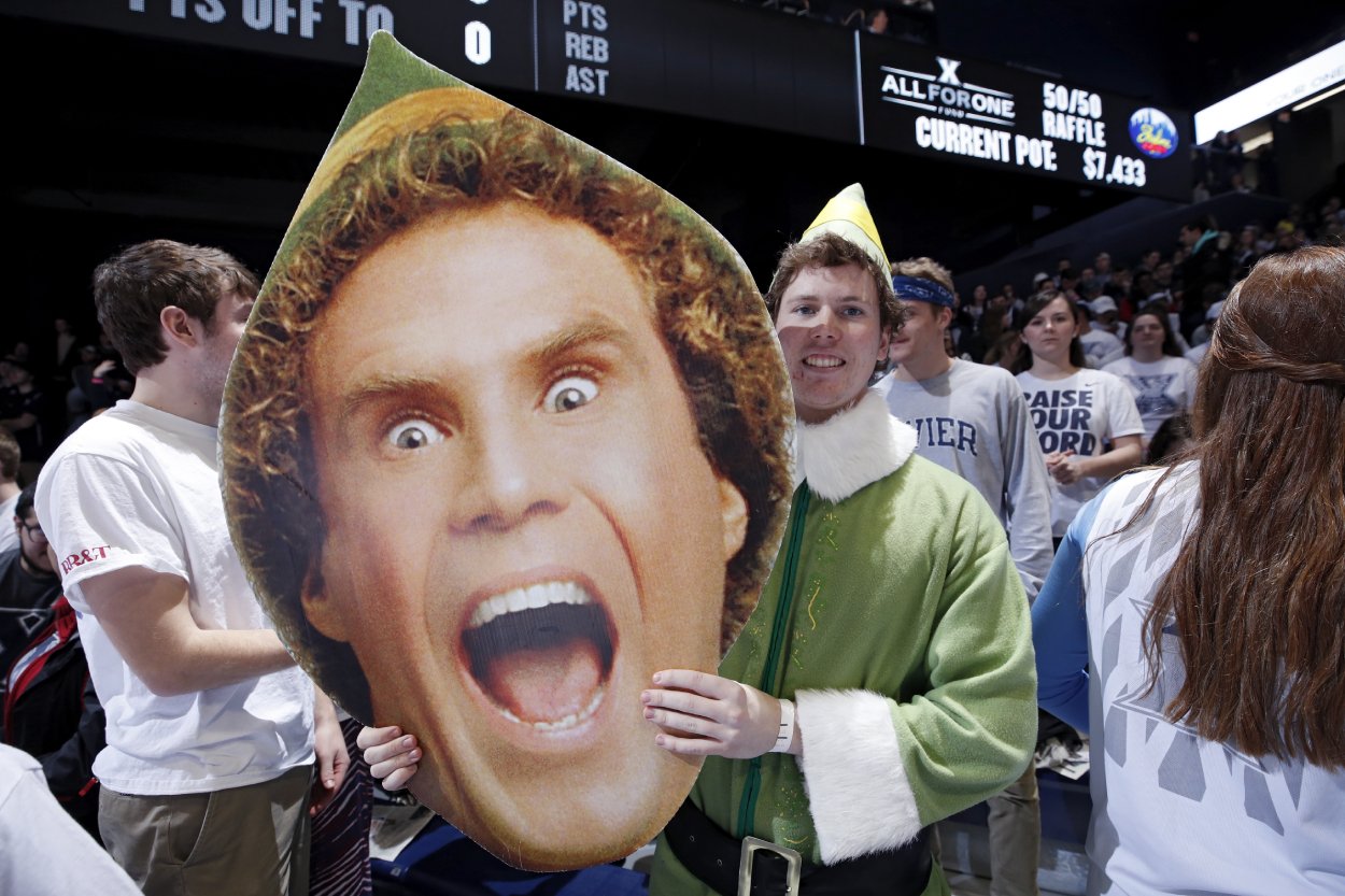 A basketball fan holds a cutout of actor Will Ferrell as Buddy the Elf before a game