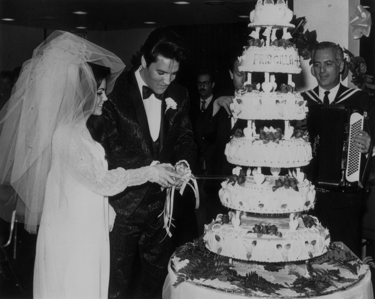 Elvis Presley (1935 - 1977) cutting the six-tier wedding cake with his bride Priscilla Beaulieu