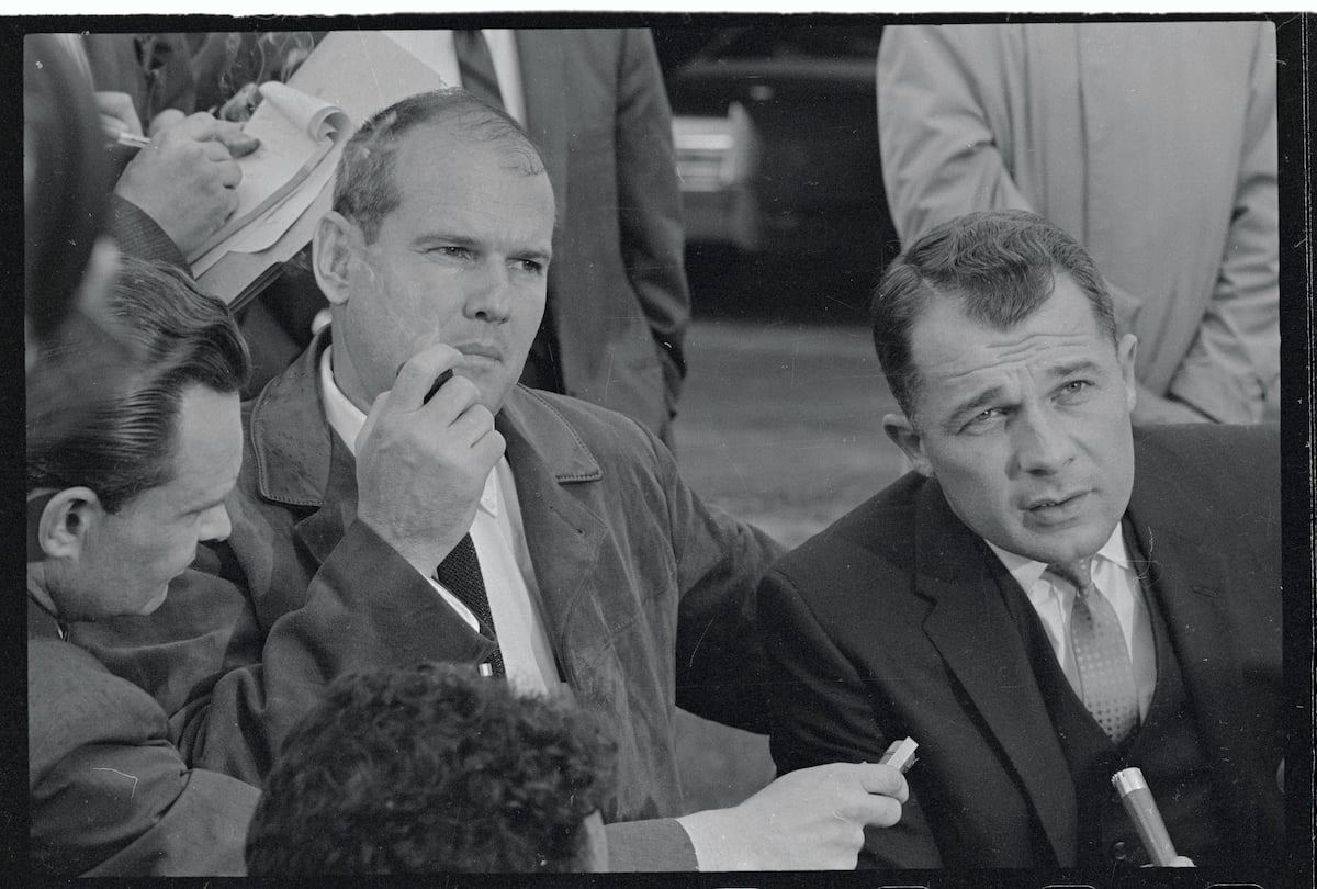 Dr. Samuel Sheppard listens as his attorney, F. Lee Bailey, answers news men's questions outside the home of Sheppard's brother Richard