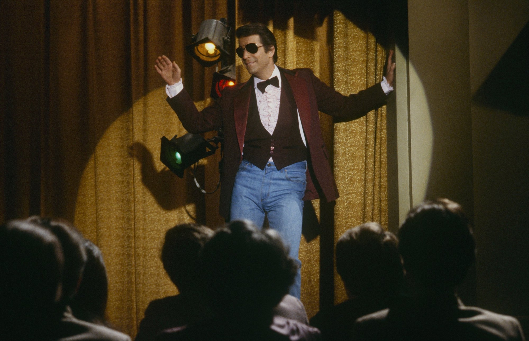 Henry Winkler as Fonzie on Happy Days, standing on a stage wearing sunglasses
