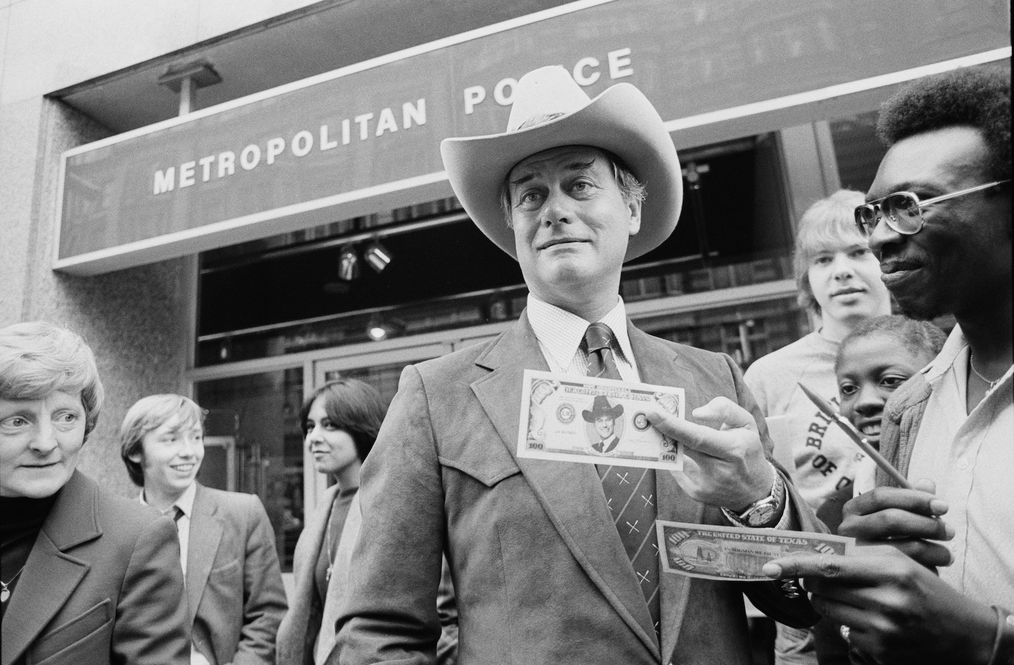 Larry Hagman smiling slightly, wearing a cowboy hat, in black and white